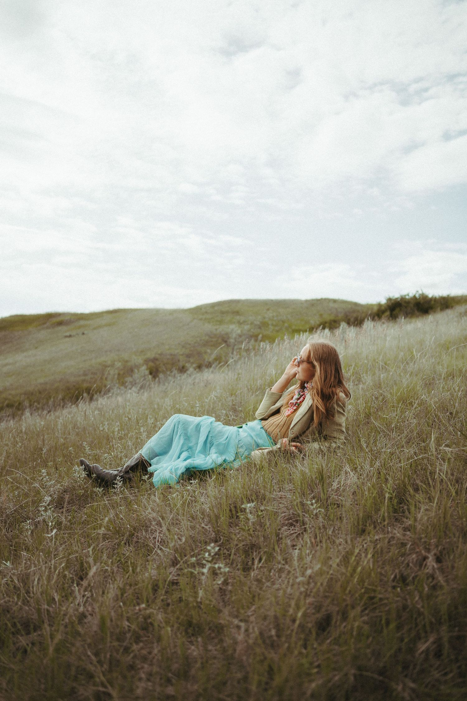 A woman lays in the field. She is wearing a vibrant outfit