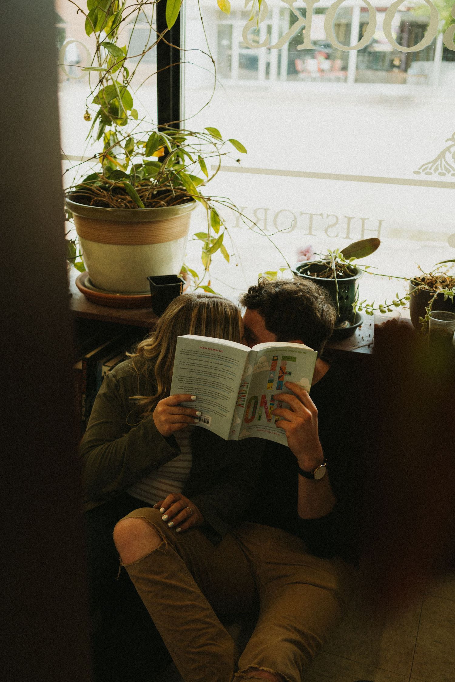 A couple hides their faces behind a book at the bookstore