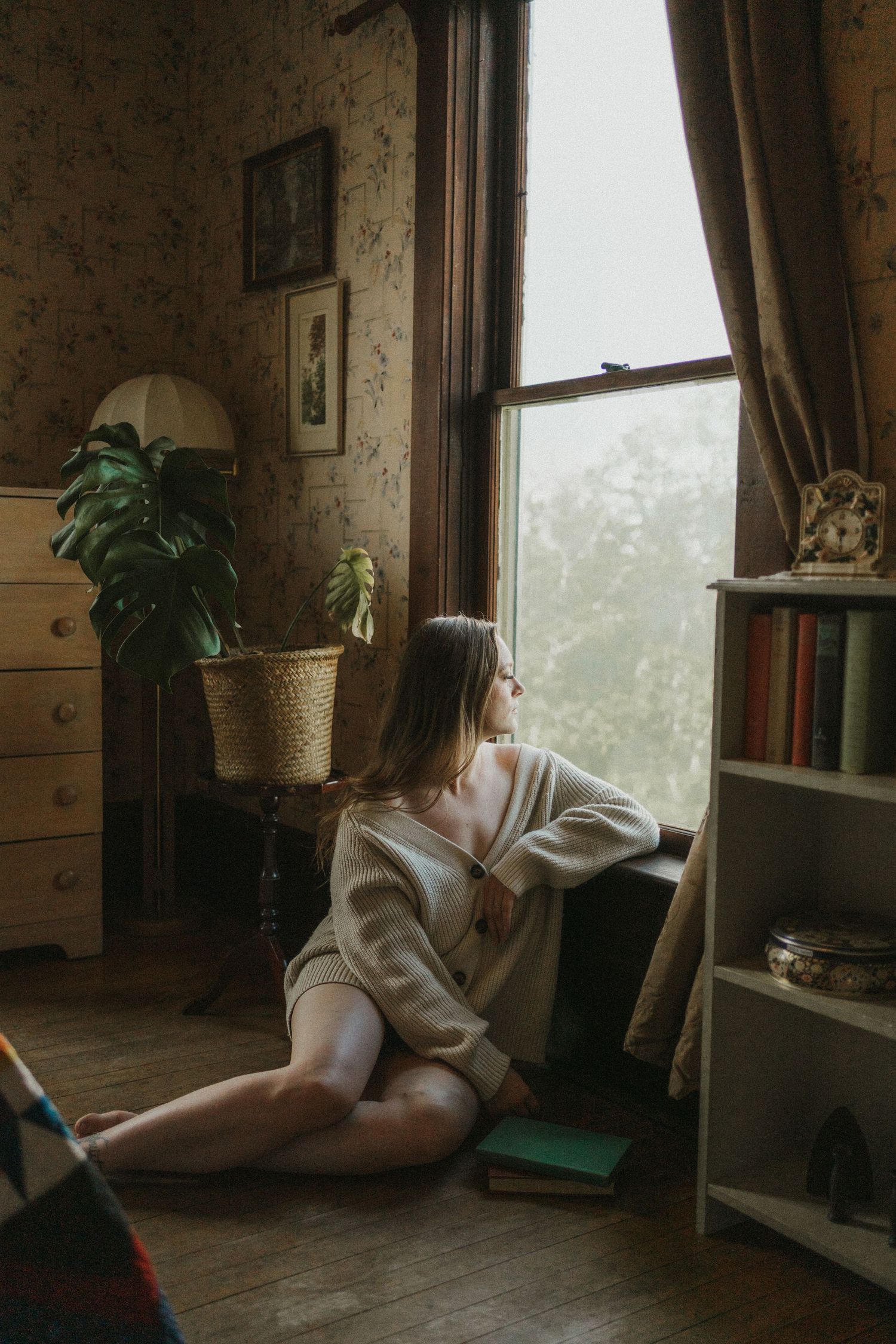 A photo of a woman sitting by a window. Candid, moody.