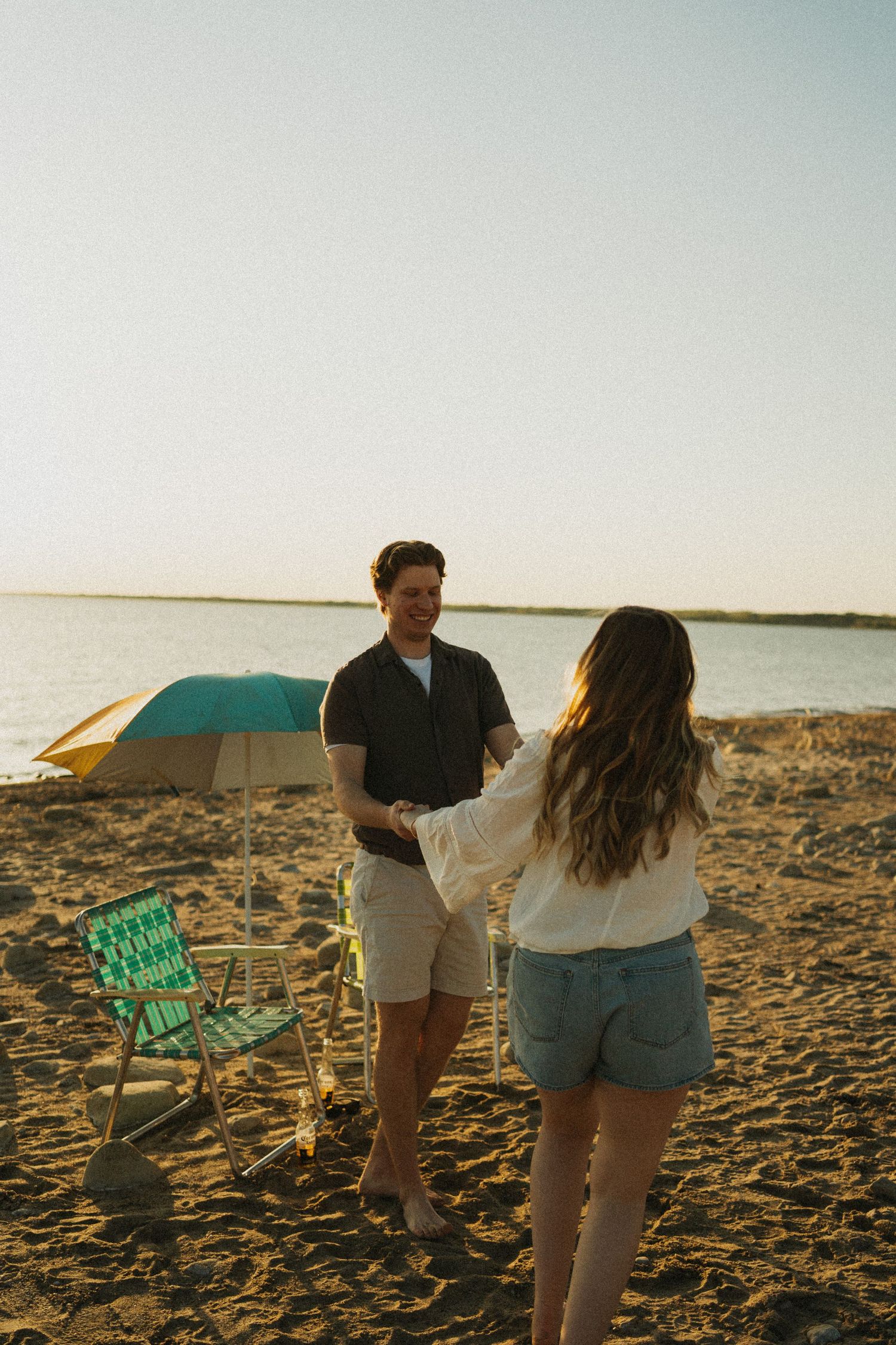 A couple spins around at the beach. There is a retro vibe to the photo.