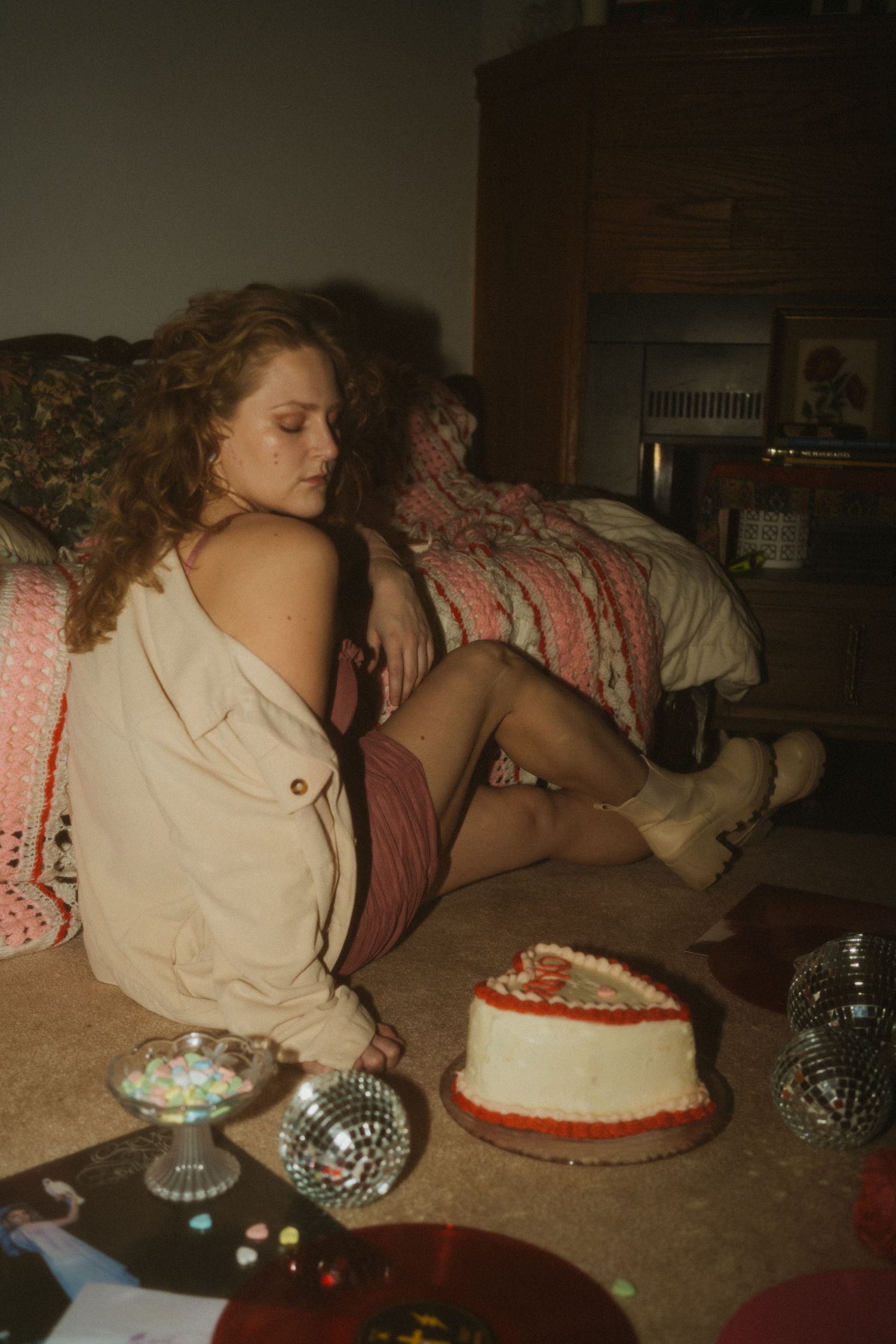 A woman celebrates valentines day with a cake, disco balls and records