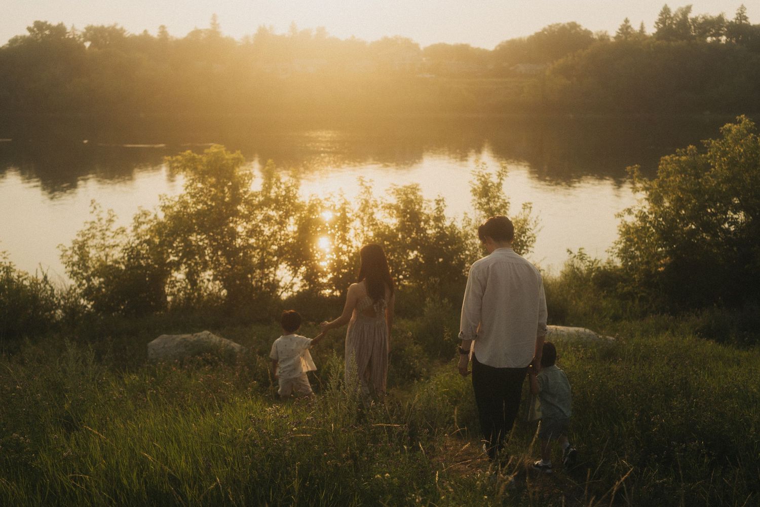 A dreamy, golden hour family photoshoot. Candid photo of the family walking by the river.