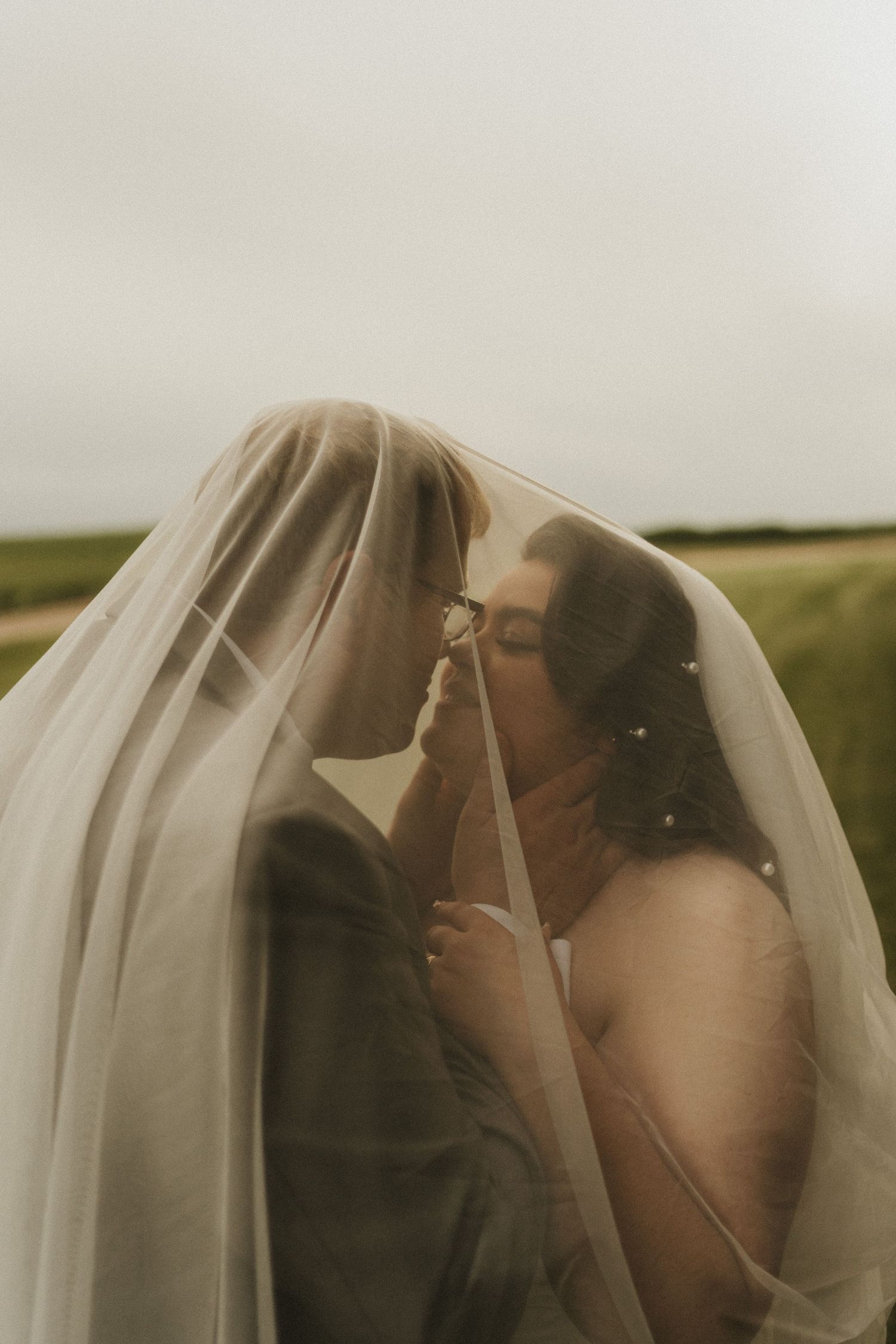 A photo of a wedding couple under the veil at golden hour.