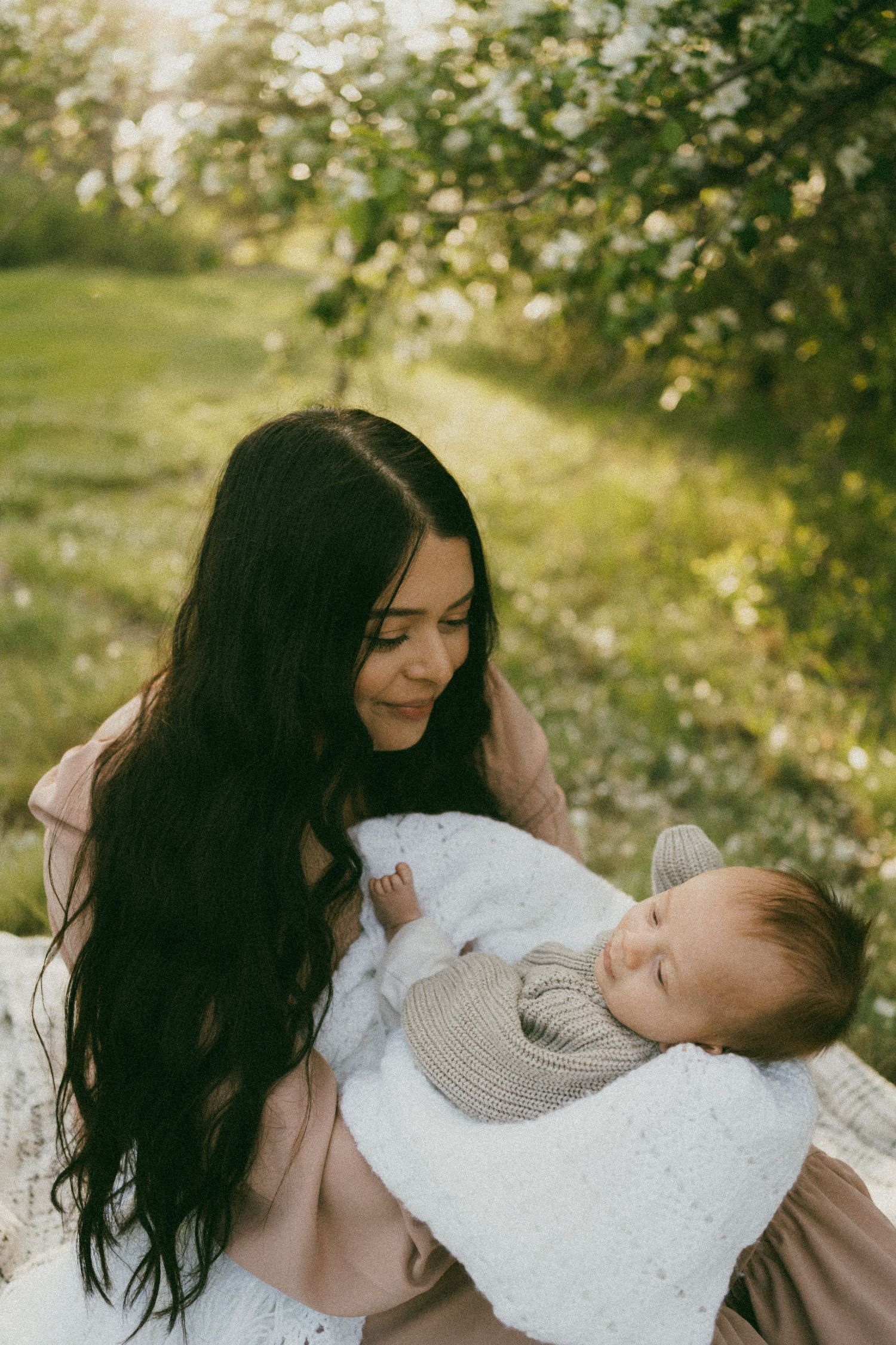 a mother looks at her baby in the blossoms