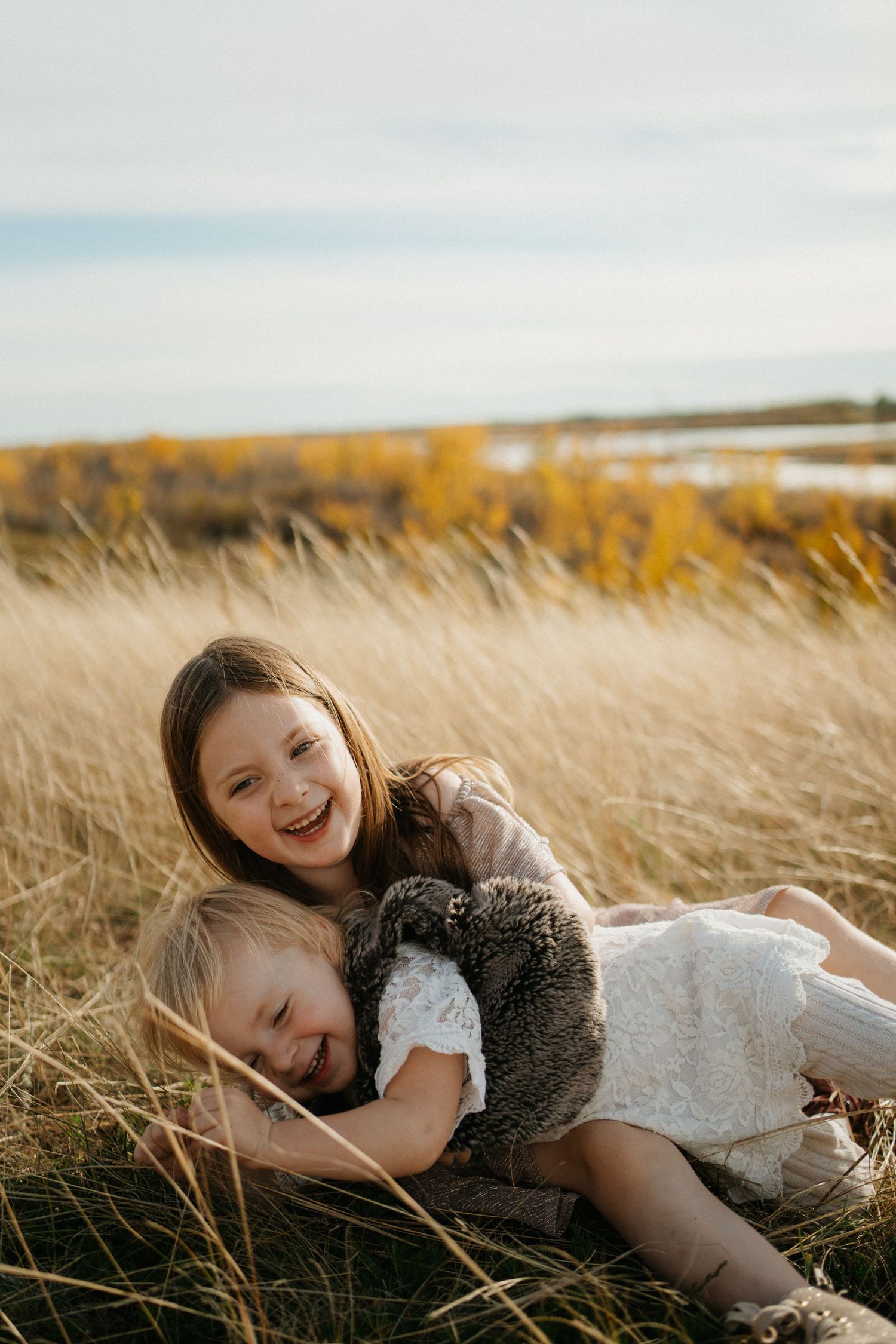 two siblings roll around in the grass