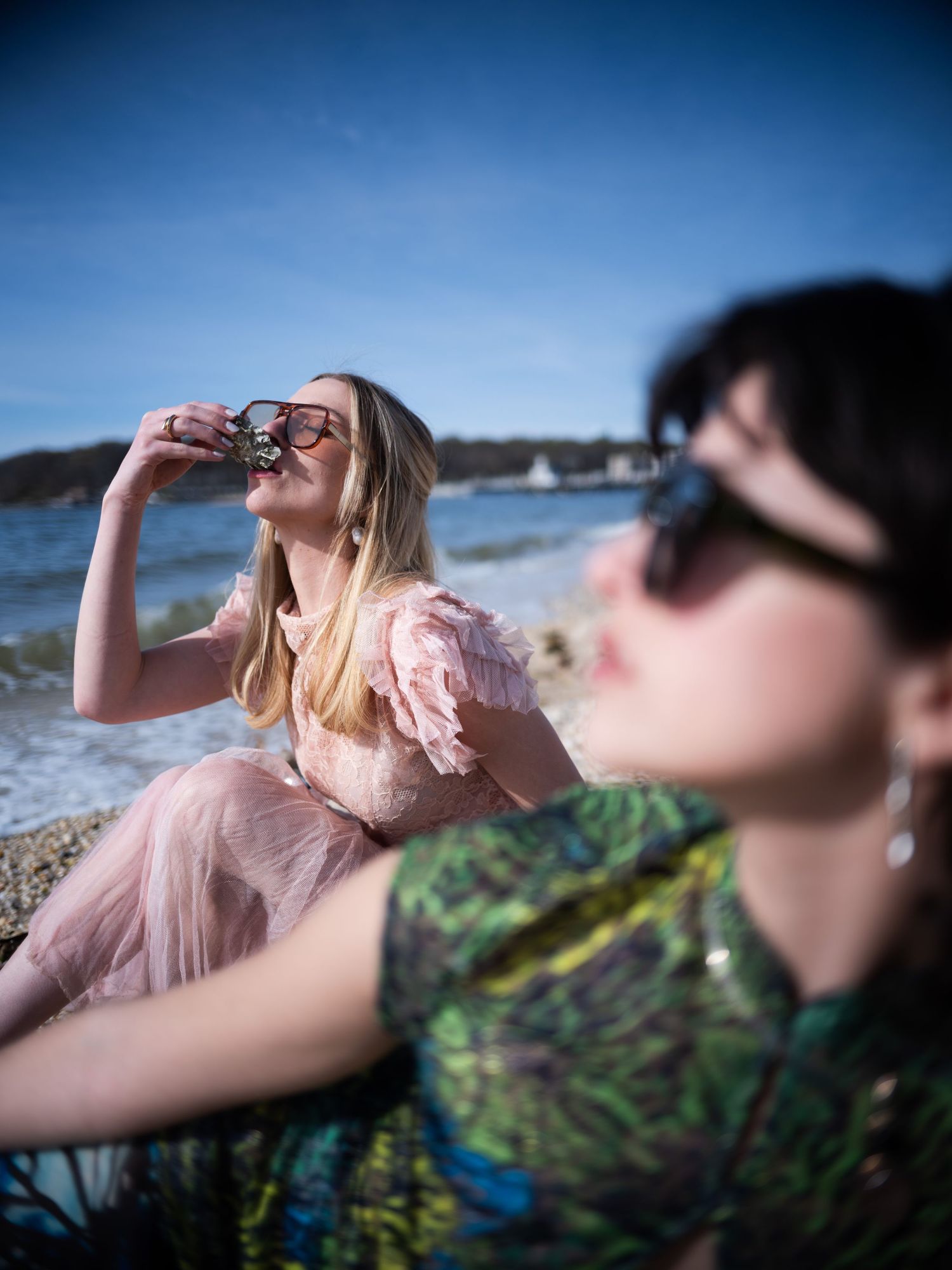 People drinking and enjoying beverages at a beach on a sunny day with ocean views in the background.