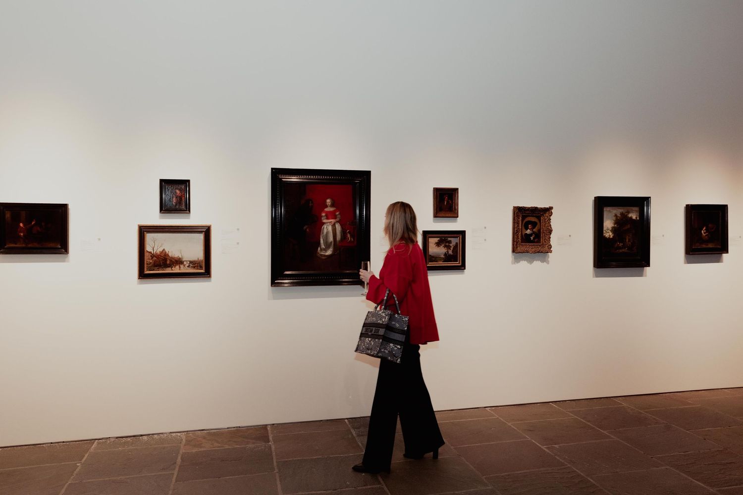 Art gallery visitors view photographs displayed in a minimalist white exhibition space with framed works mounted on walls.