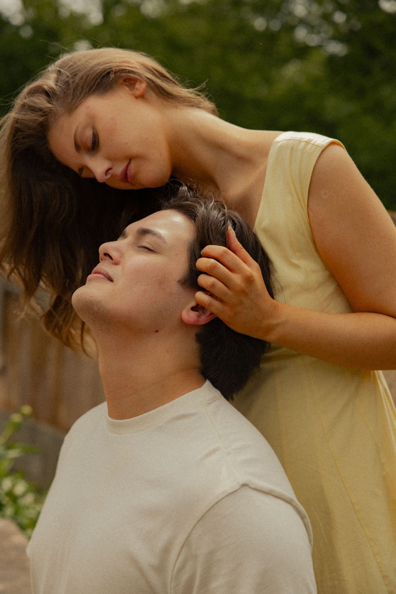 Tender moment as a young woman gently touches a man's hair outdoors.