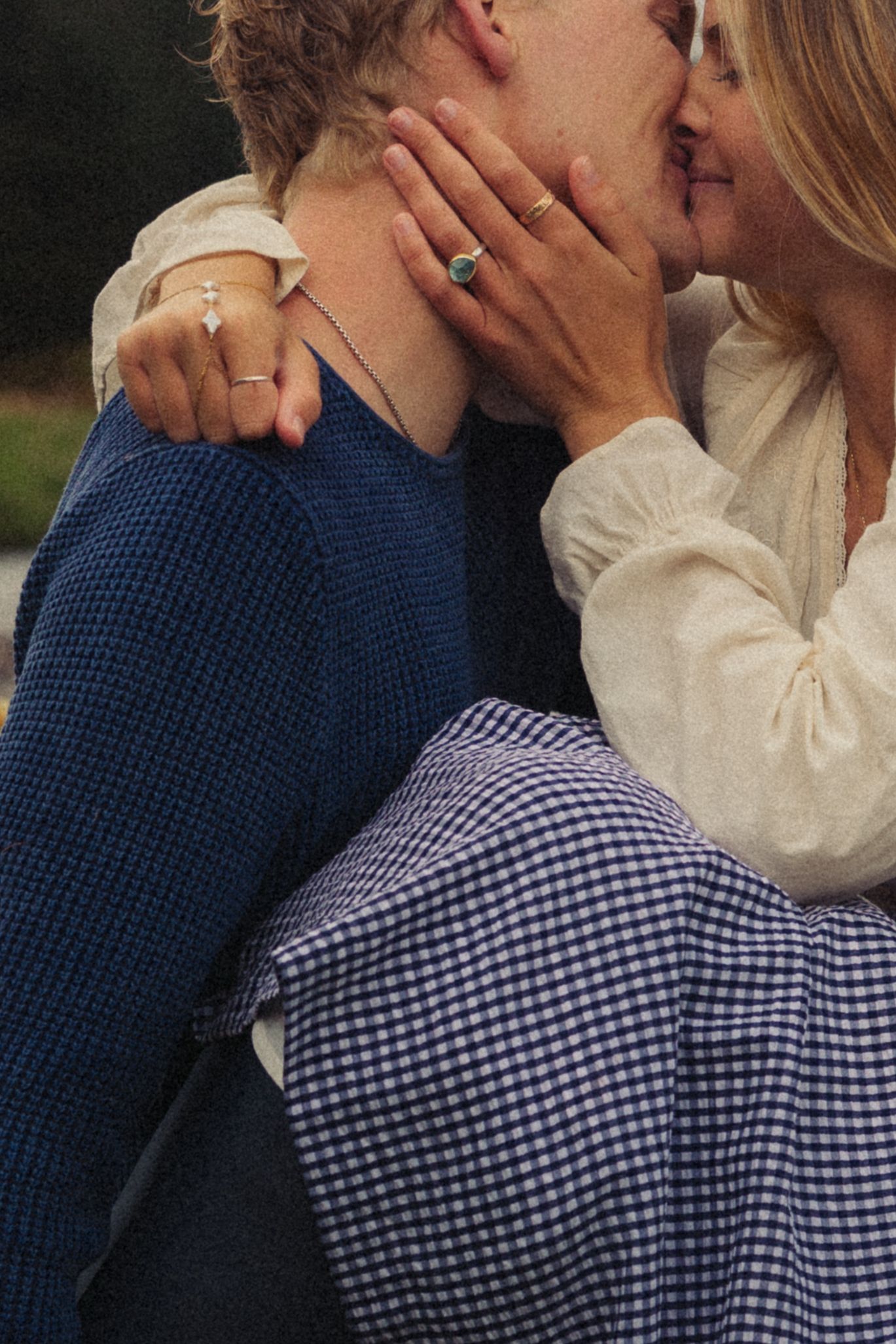 Close-up of couple sharing kiss, woman wearing elegant rings embracing partner.