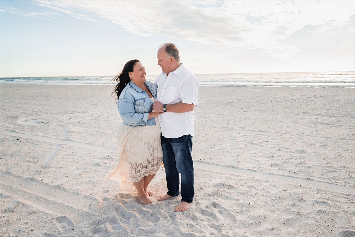 Happy couple dancing together on sandy beach at sunrise.