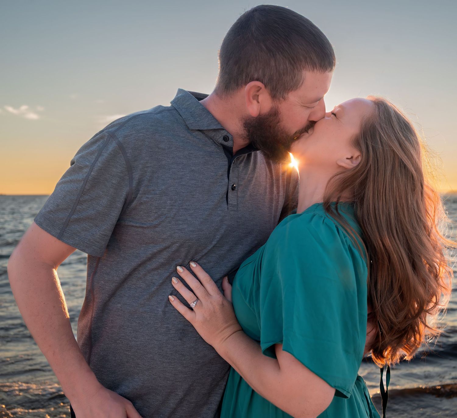 Couple sharing romantic kiss at beach during stunning sunset.