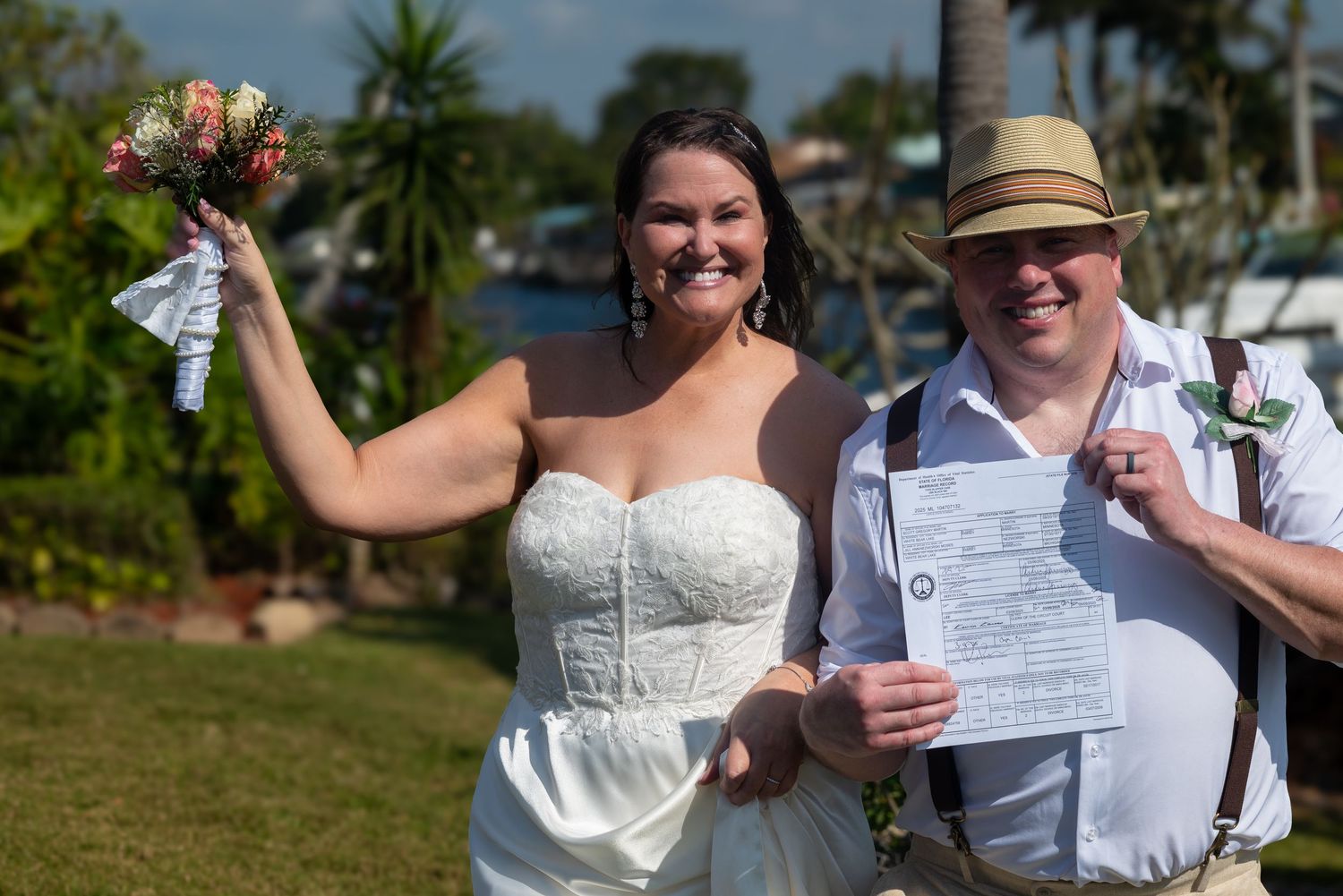 Joyful newlyweds celebrate after ceremony, bride raising bouquet as groom displays marriage certificate.