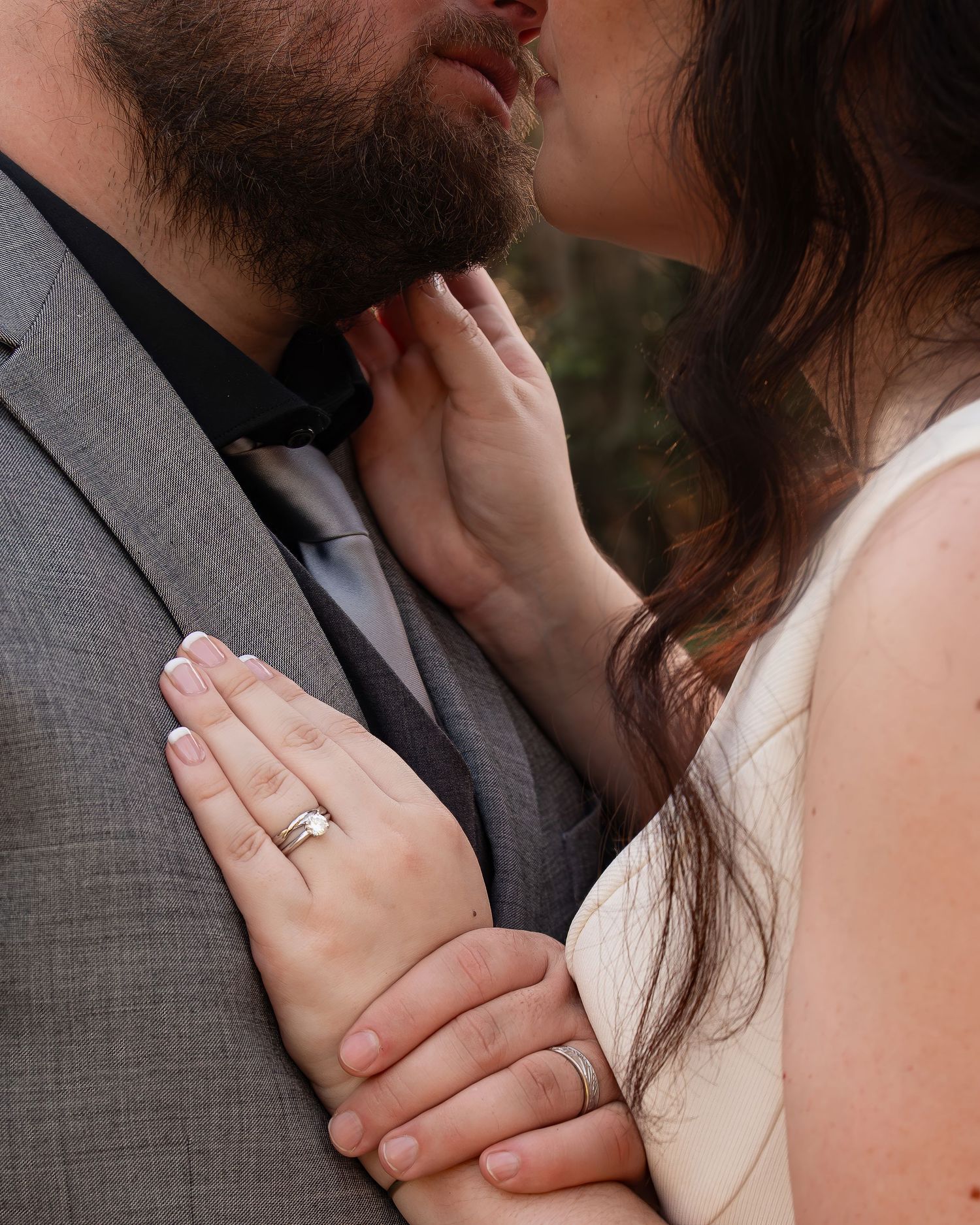 Close-up of bride and groom nearly kissing, showcasing wedding rings on the bride's hands.