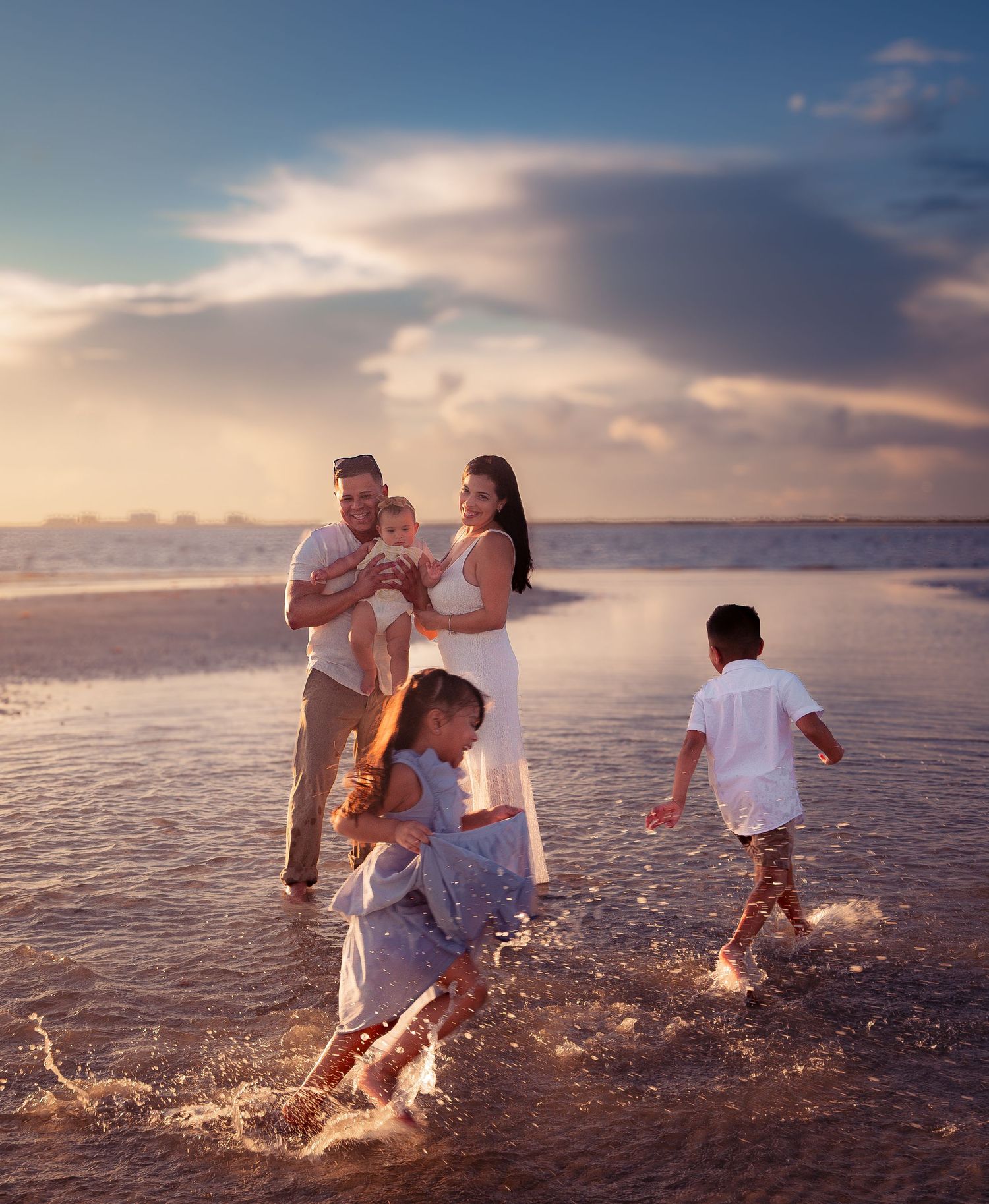 Happy family with children playing in ocean waves at sunset on a beautiful beach.
