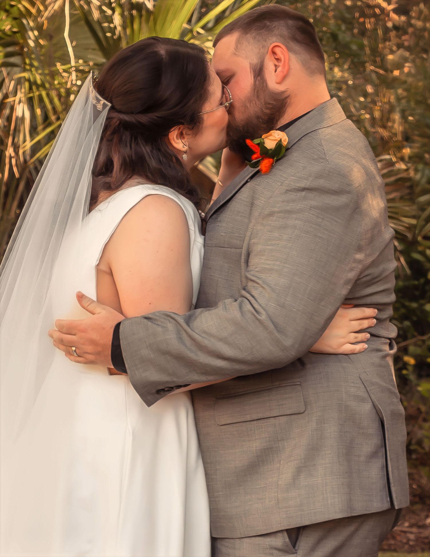 Bride and groom share a romantic first kiss at their outdoor wedding ceremony.