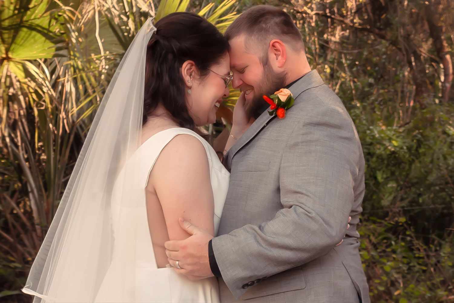Bride and groom share an intimate forehead touch in a lush garden setting.