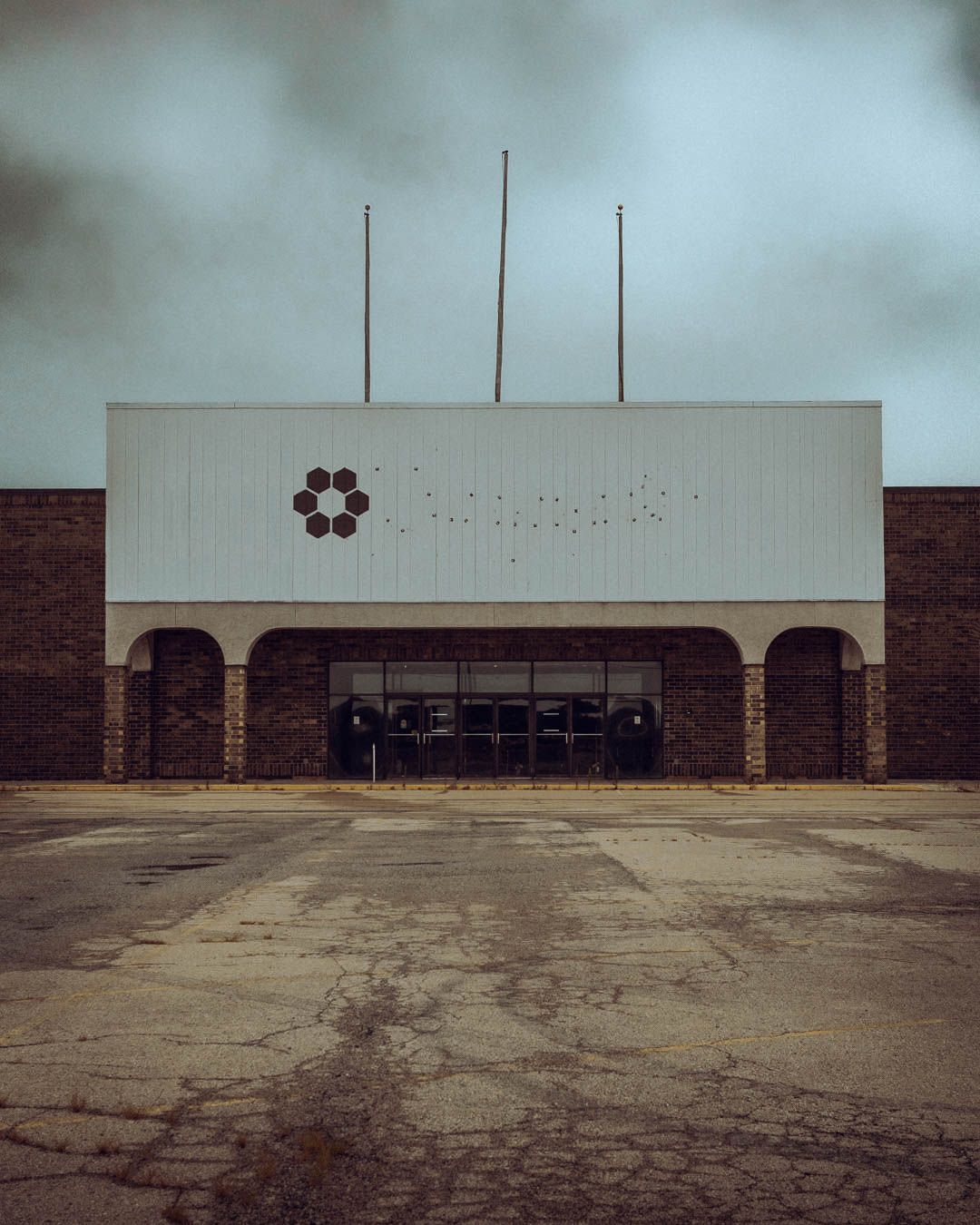 A series of abandoned storefront facades with brick walls and white upper sections shown in a desaturated style.