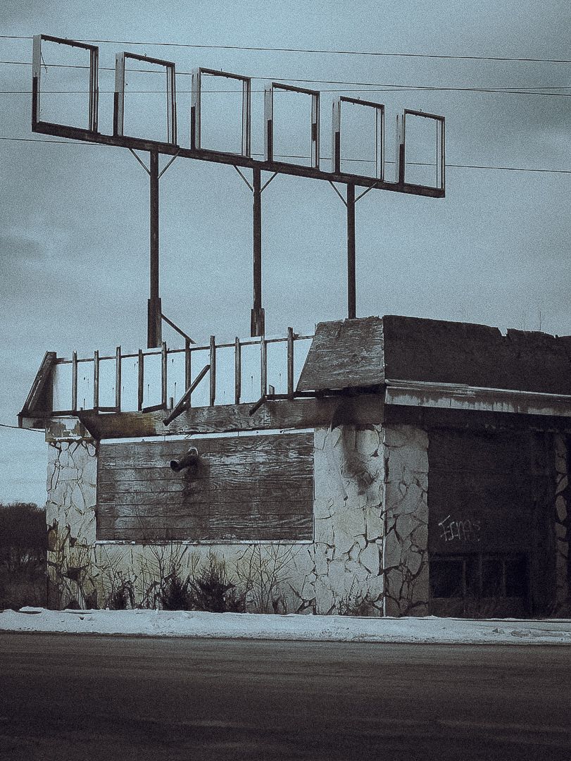 A black and white panoramic photo shows a concrete wall with graffiti against a stark industrial backdrop.