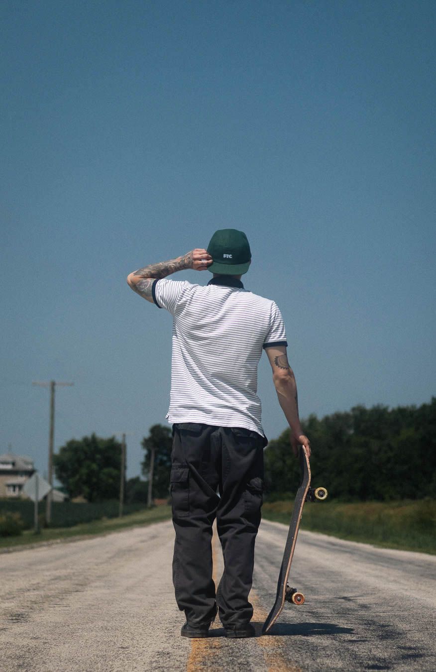 A skateboarder performs a sequence of tricks on an empty rural road on a sunny day.