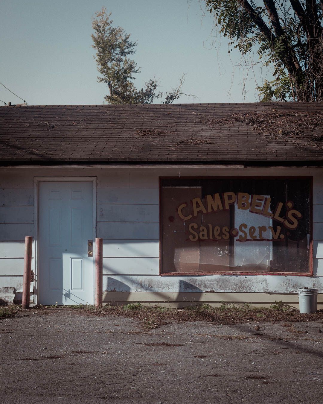 Abandoned strip mall storefront with faded signage and boarded up windows shows signs of urban decay.
