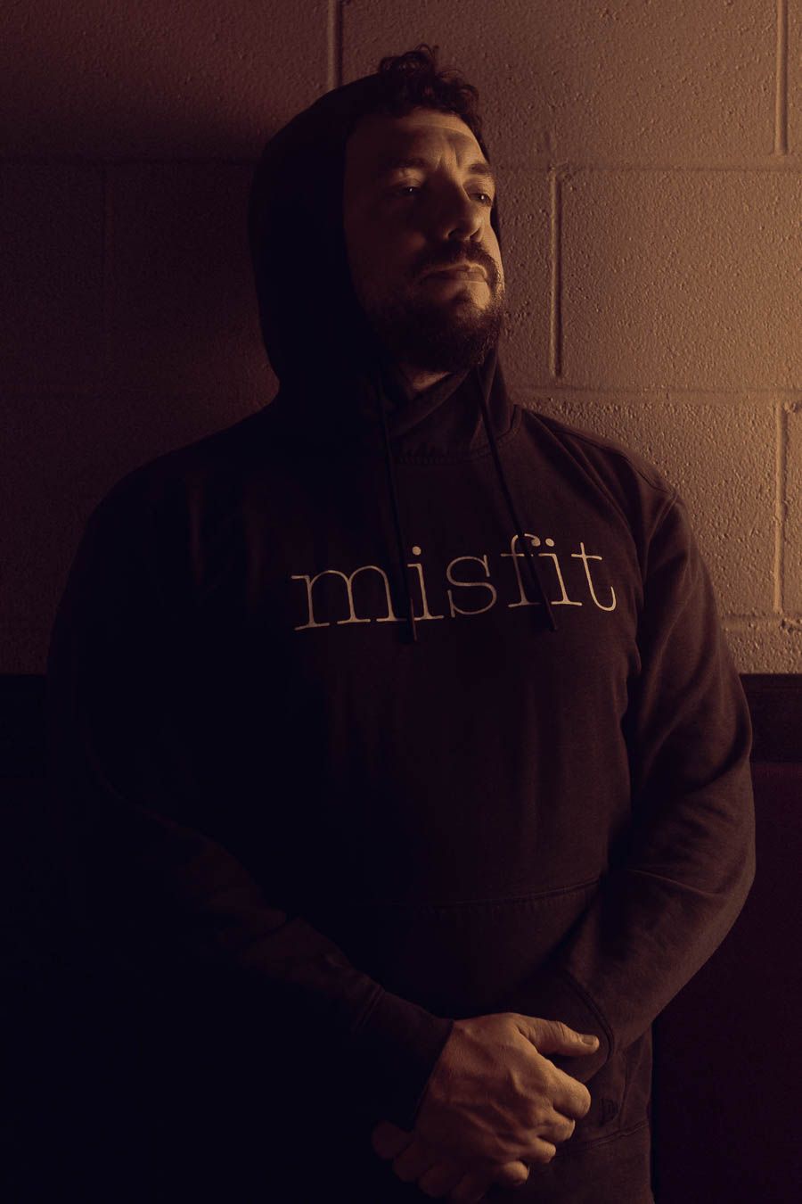 A dark, moody sequence of photos showing someone in a black hoodie against a dimly lit wall with text.