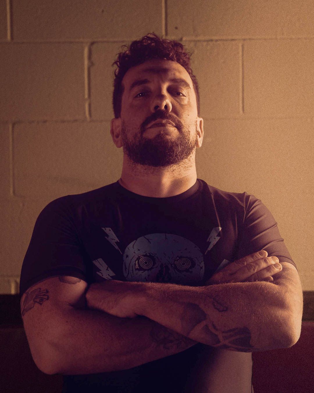 A series of dimly lit portraits showing a person with crossed arms in various poses against a beige wall.