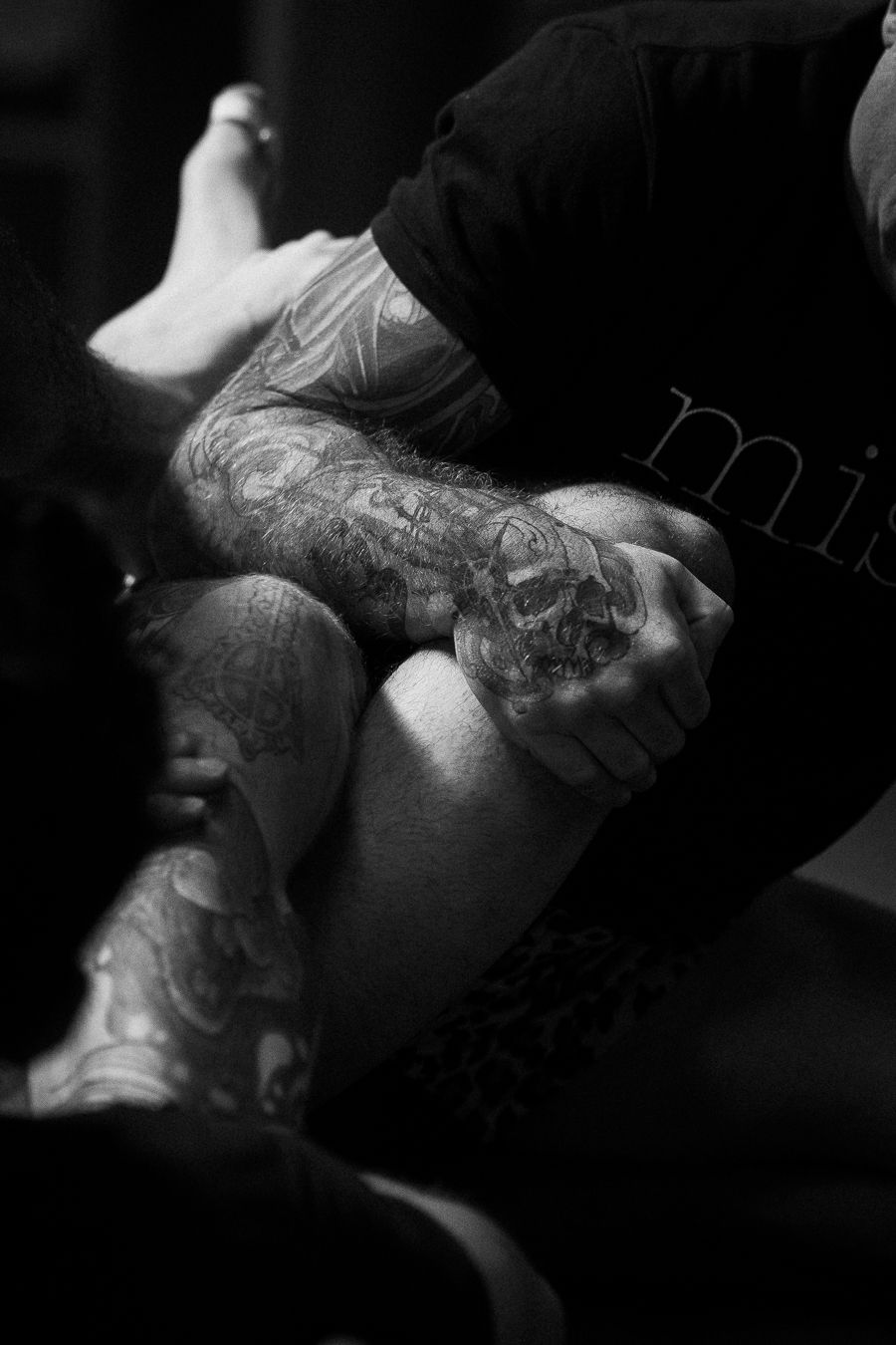 Black and white photo of tattooed arms grappling in a martial arts or wrestling match.
