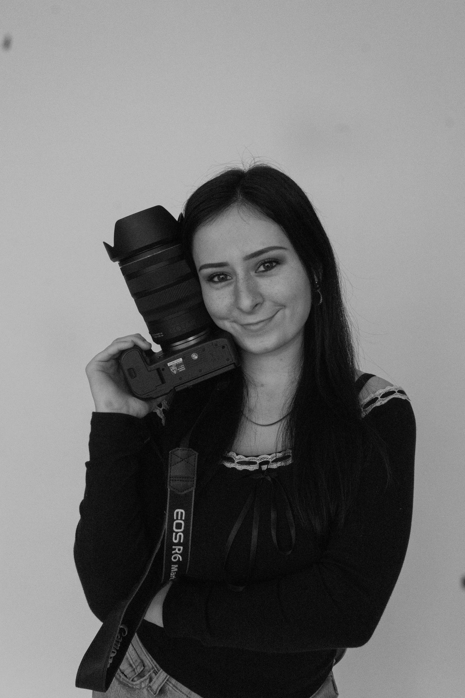 Black and white photo series showing someone posing playfully with a DSLR camera against a plain background.