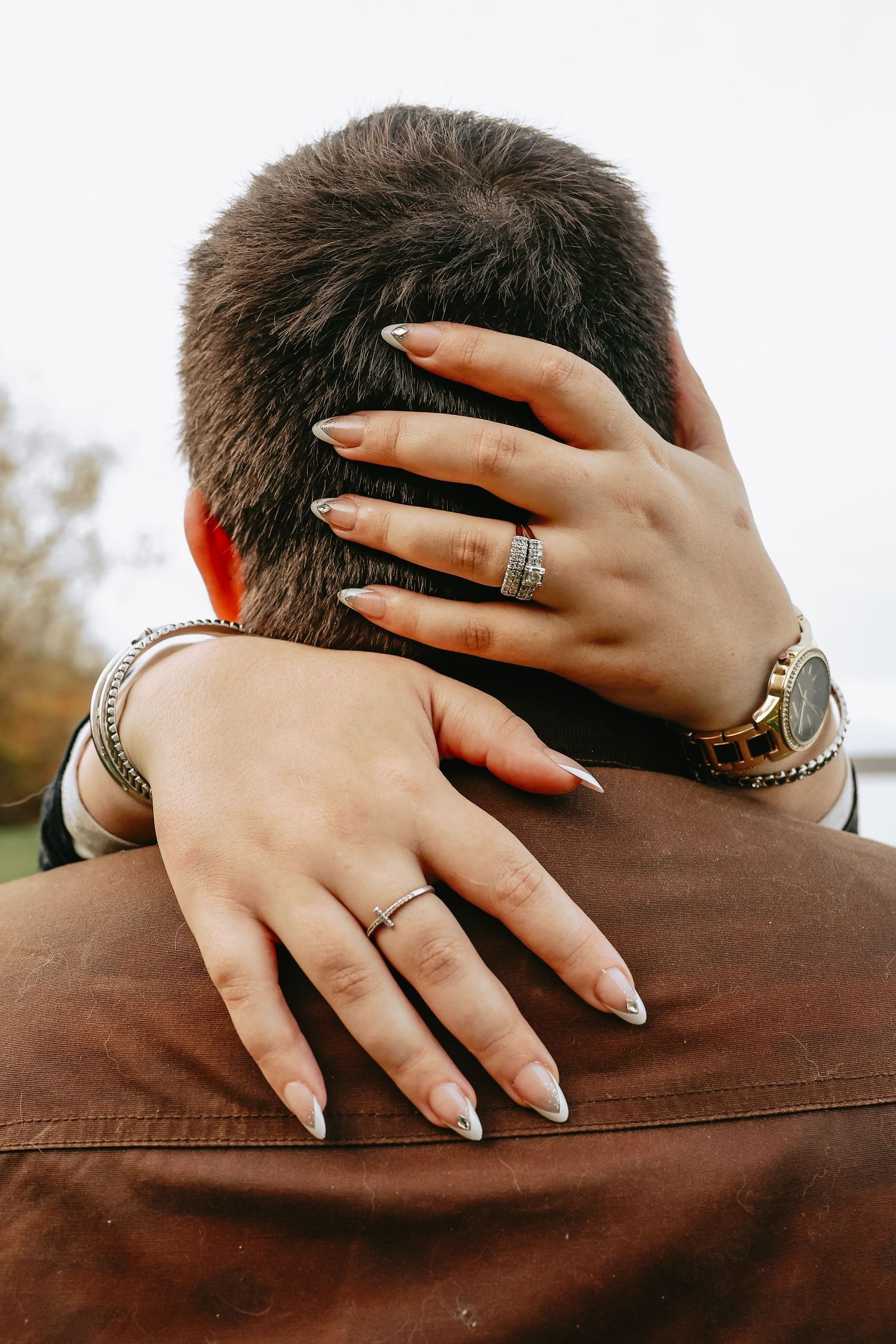 Close-up of hands with manicured nails and rings caressing a brown fabric surface in multiple angles.