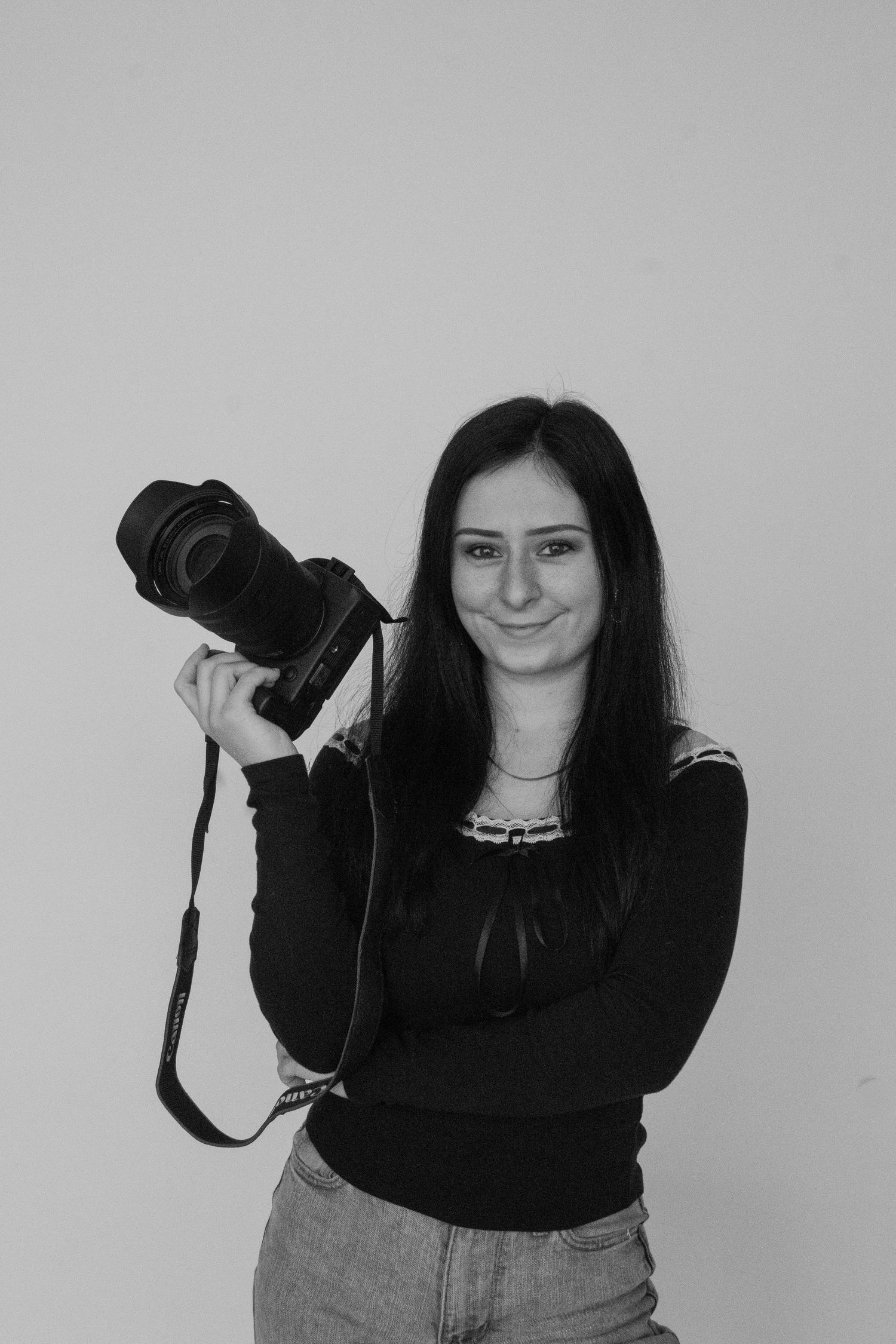 A photographer in black clothing poses with a camera against a white background in a series of artistic shots.