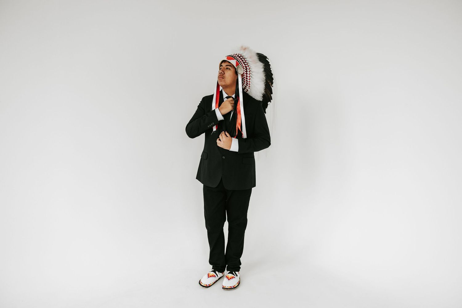 Four people in black business attire stand against a white background in different casual poses.