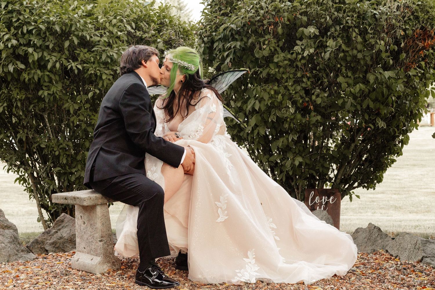 A romantic wedding couple shares tender moments in a garden setting with lush greenery and elegant attire.