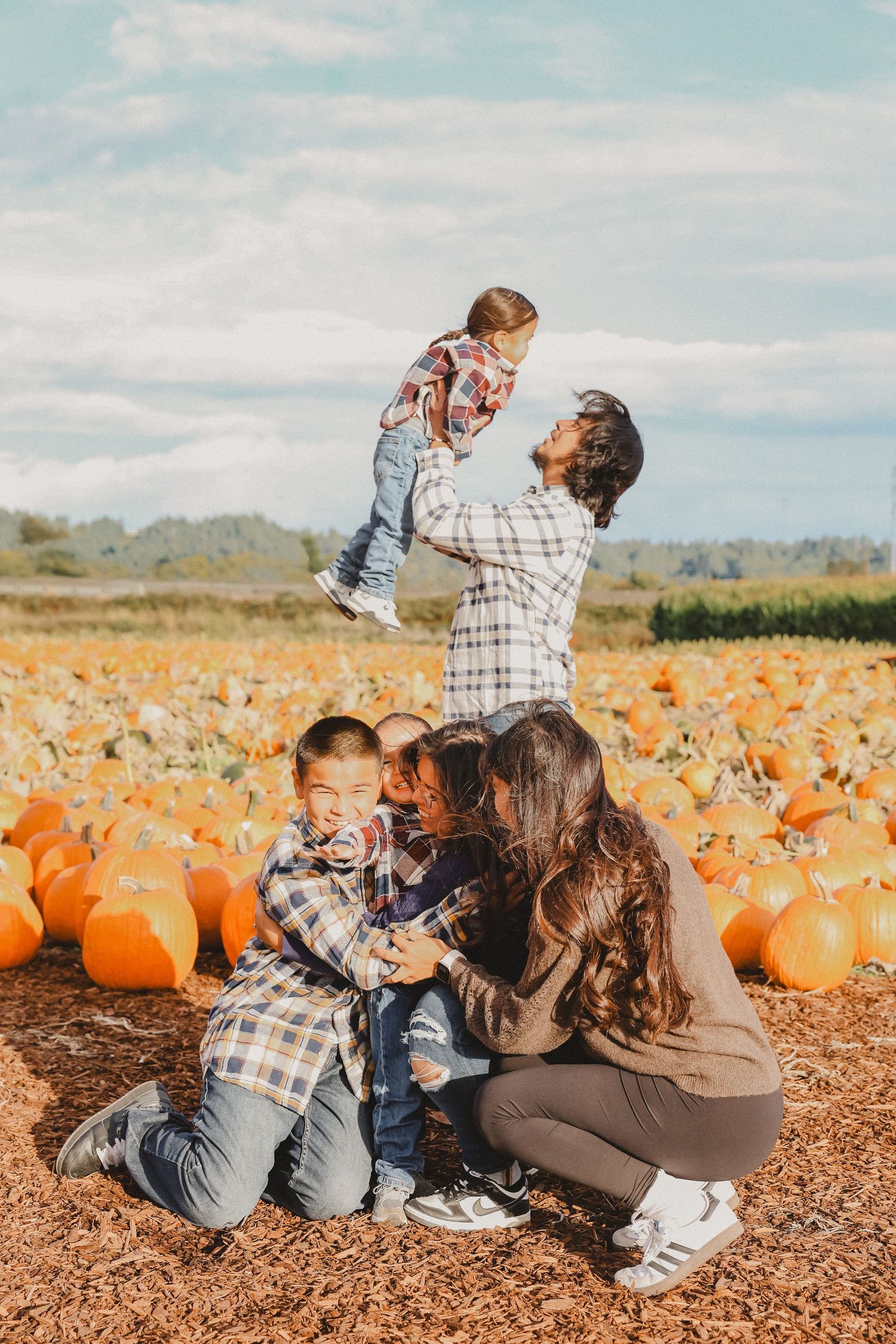 Family having fun together while visiting an autumn pumpkin patch on a sunny day.