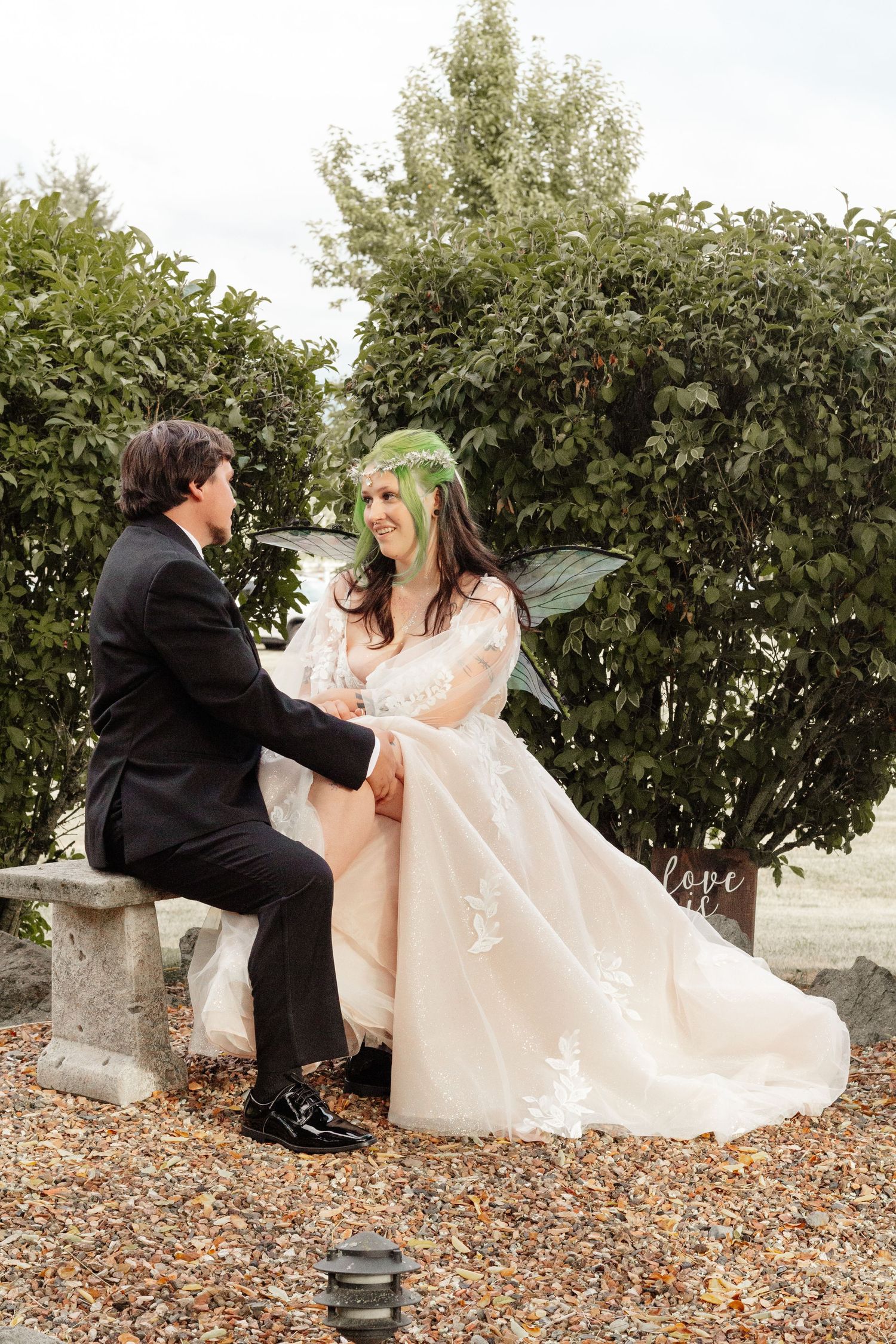 A couple in wedding attire playfully sits on autumn leaves in a sequence of romantic poses against green foliage.