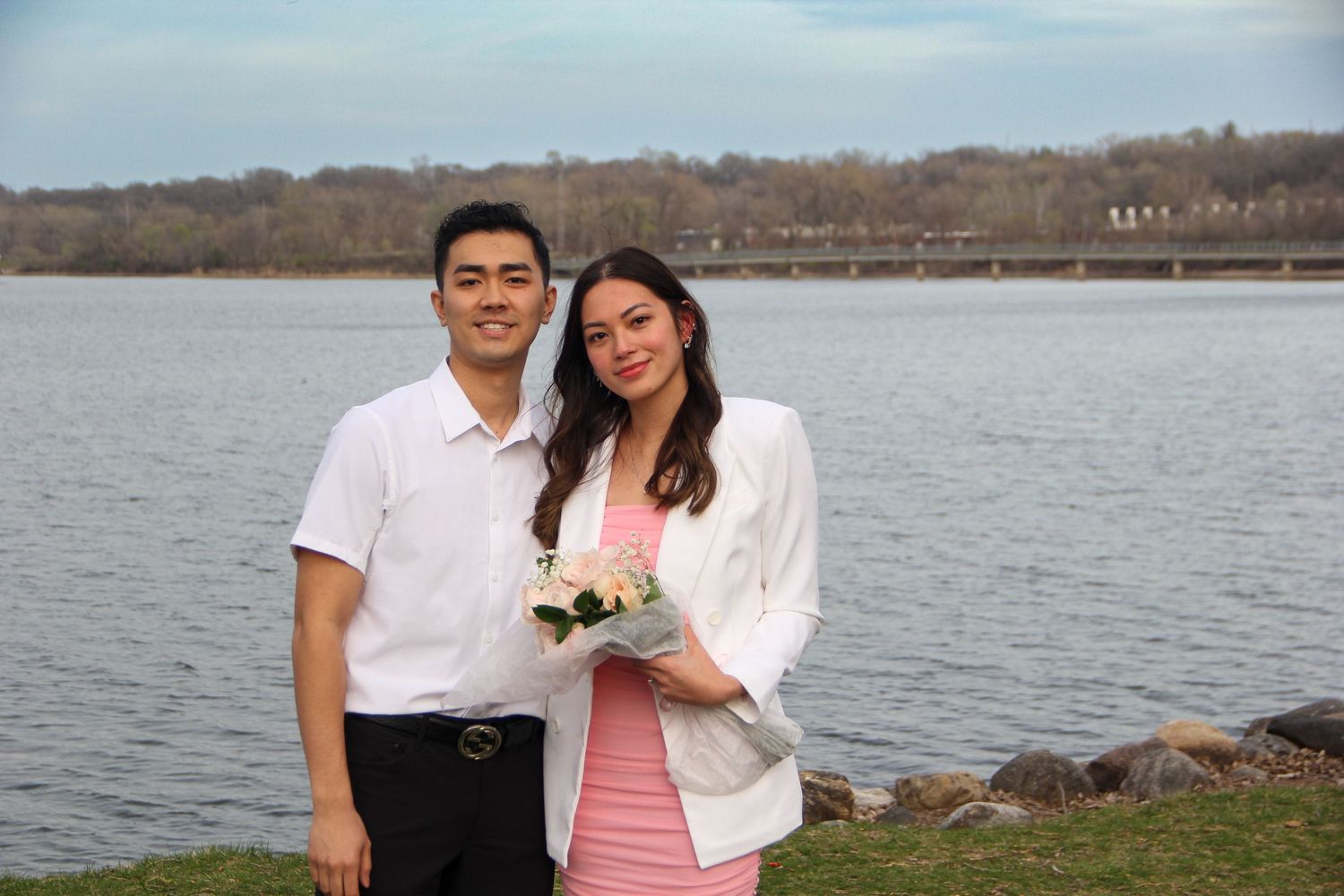 A couple embracing by a scenic lakeside on a sunny day.