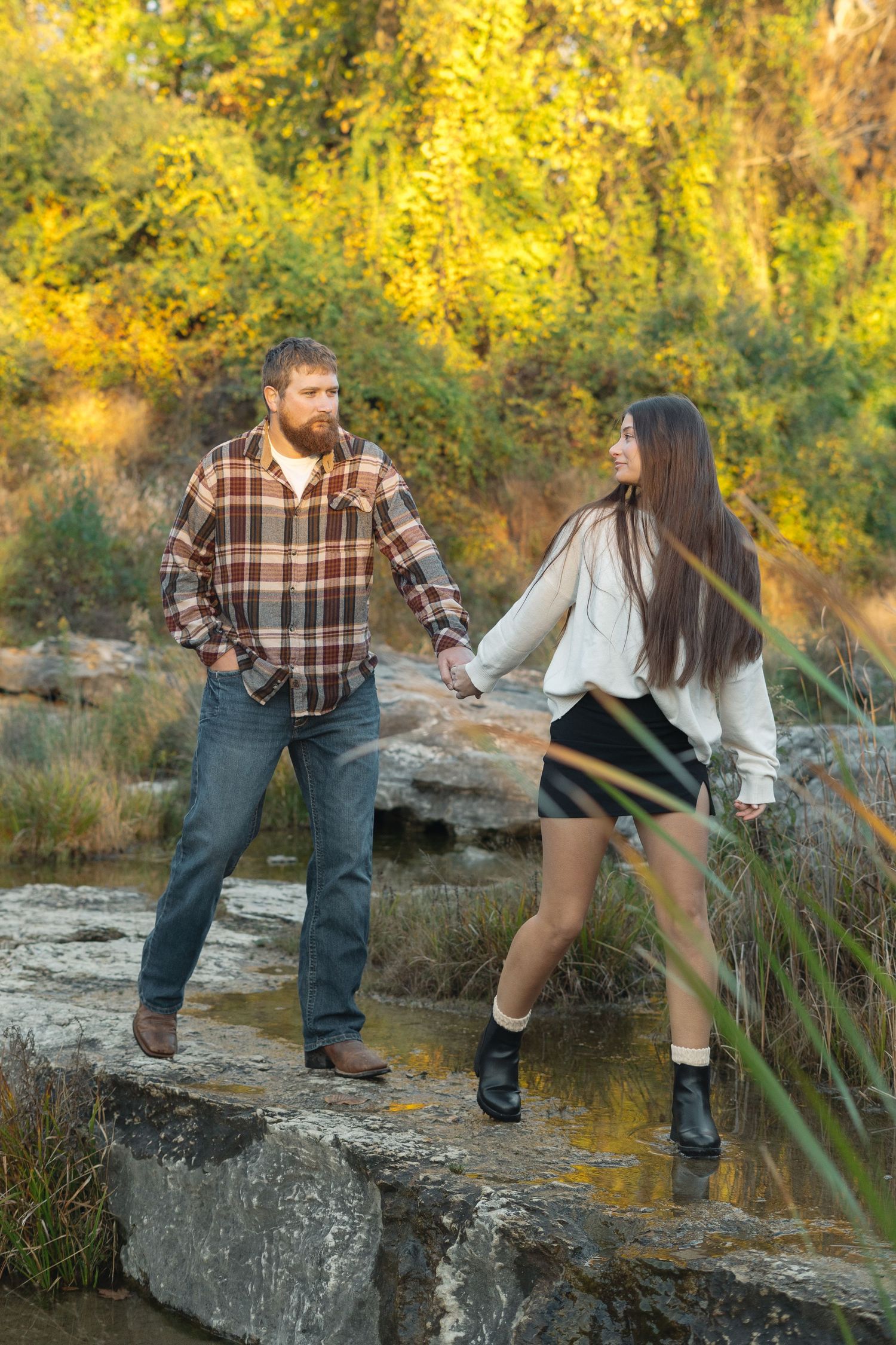 A couple enjoying an autumn day together while walking along rocky terrain surrounded by golden foliage.