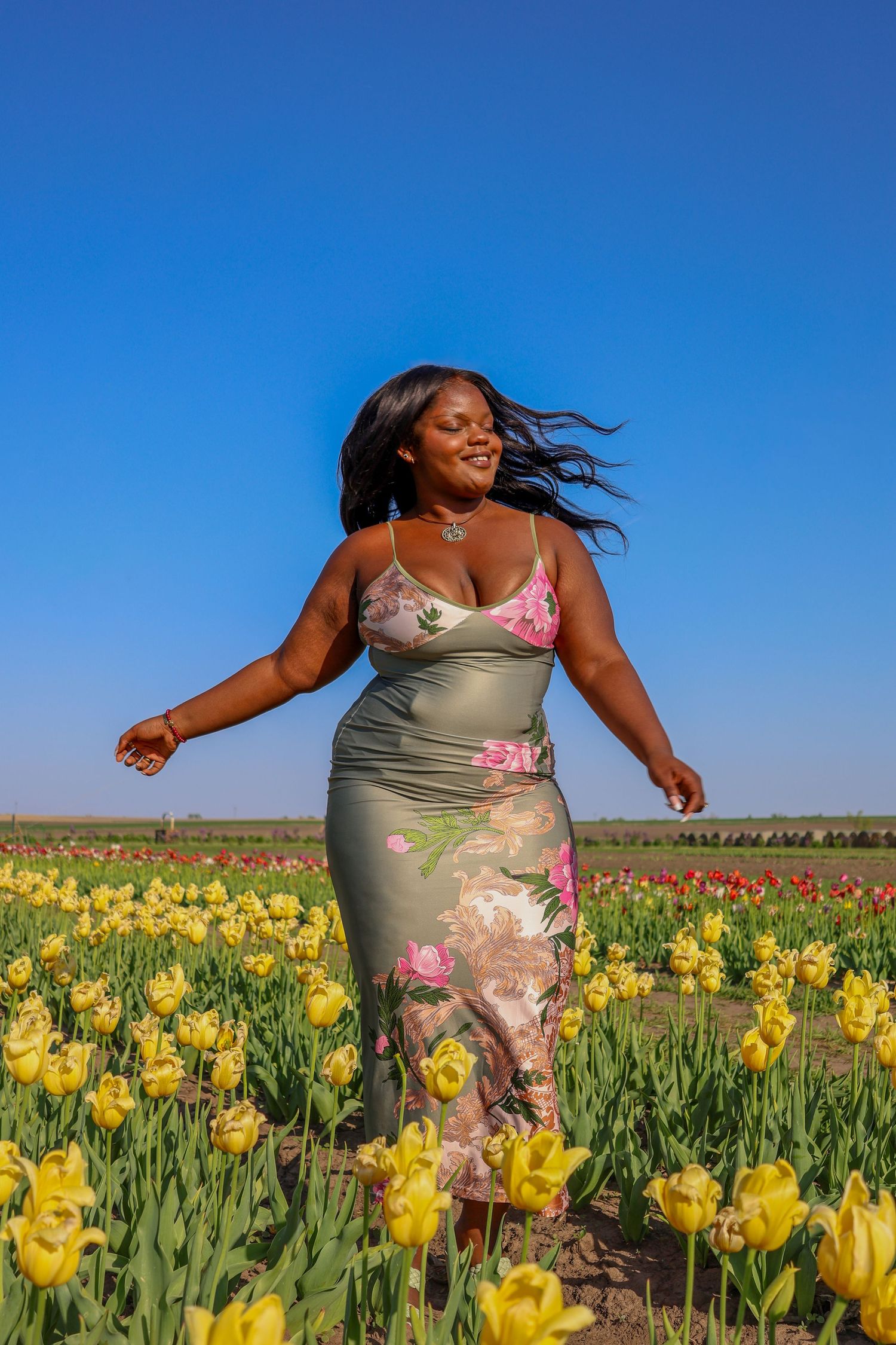 A joyful dance through a field of bright yellow tulips under clear blue skies.
