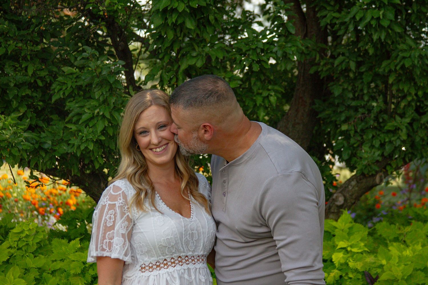 A romantic moment captured in a garden setting with colorful flowers in bloom.