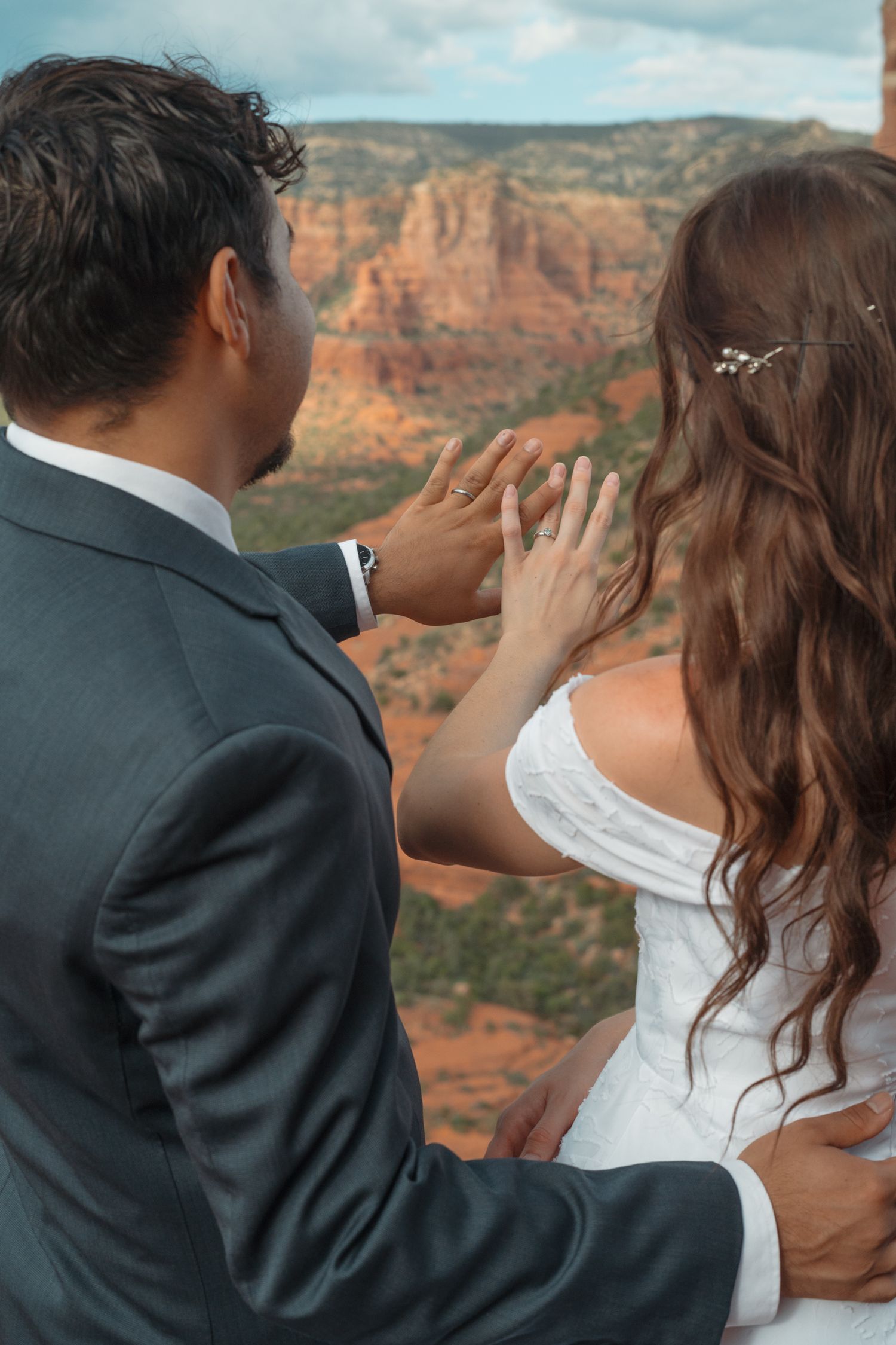 Newlywed couple showing wedding rings with stunning Sedona red rock canyon backdrop on their wedding day.