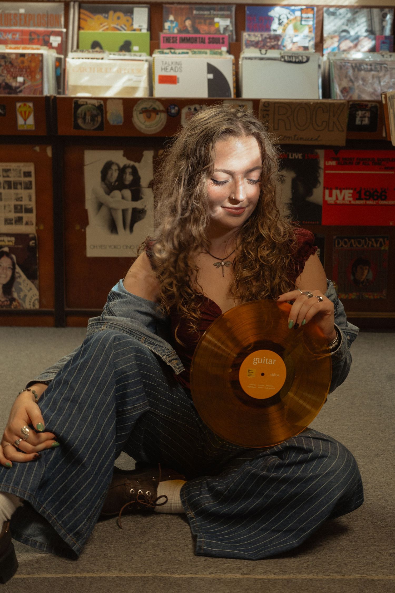A person in a pinstripe suit lies on the floor holding a vintage vinyl record in an artistic photo series.