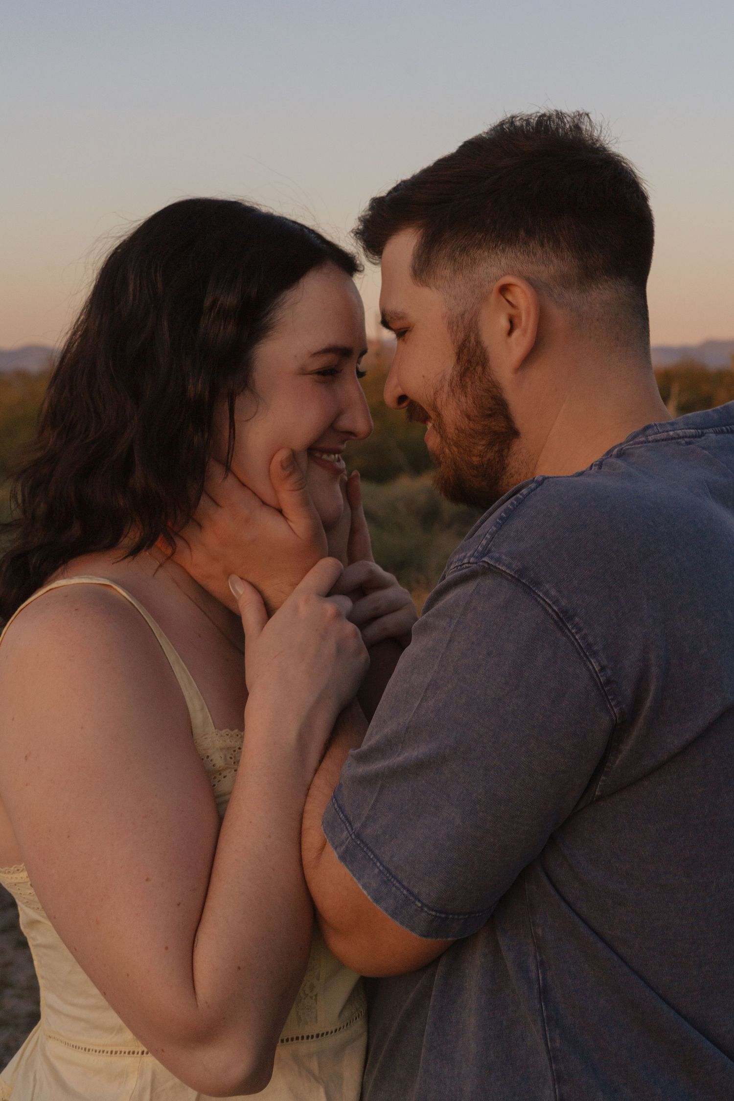 A romantic couple shares tender moments at sunset in a desert landscape.