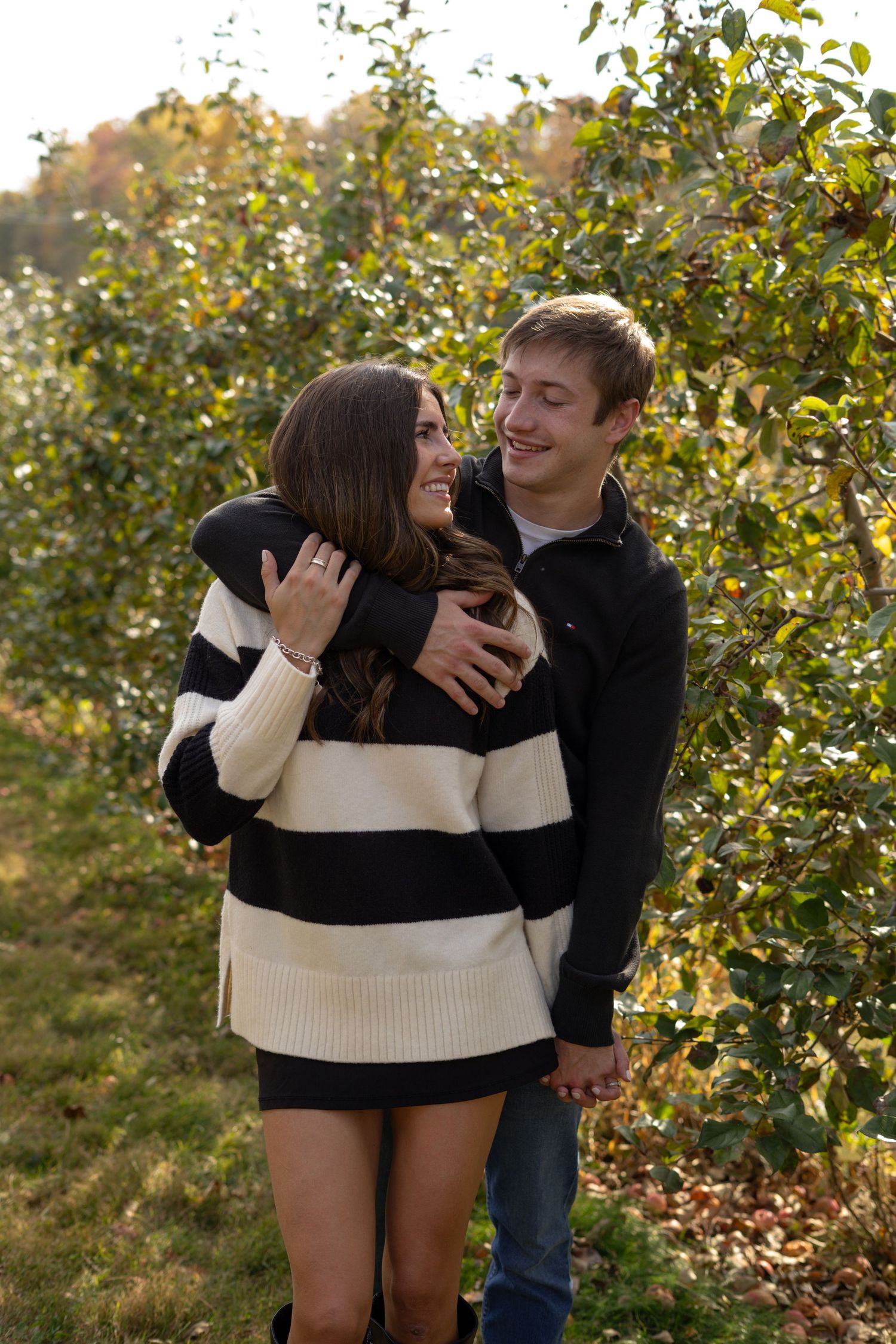 A couple shares a tender moment among autumn trees and foliage.