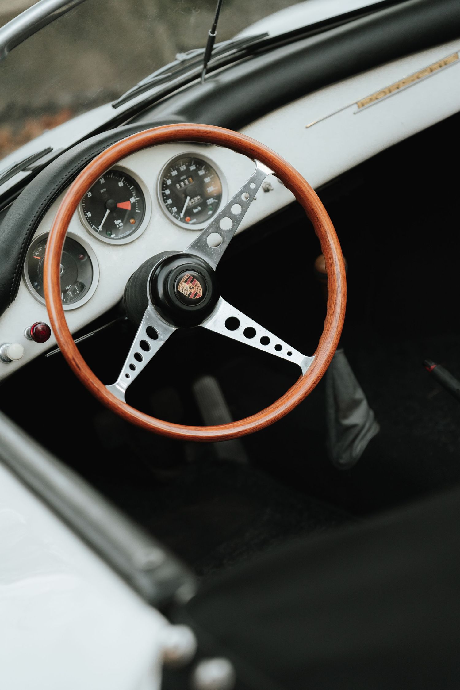 Classic wooden steering wheel and dashboard gauges of a vintage Porsche sports car shown from multiple angles.