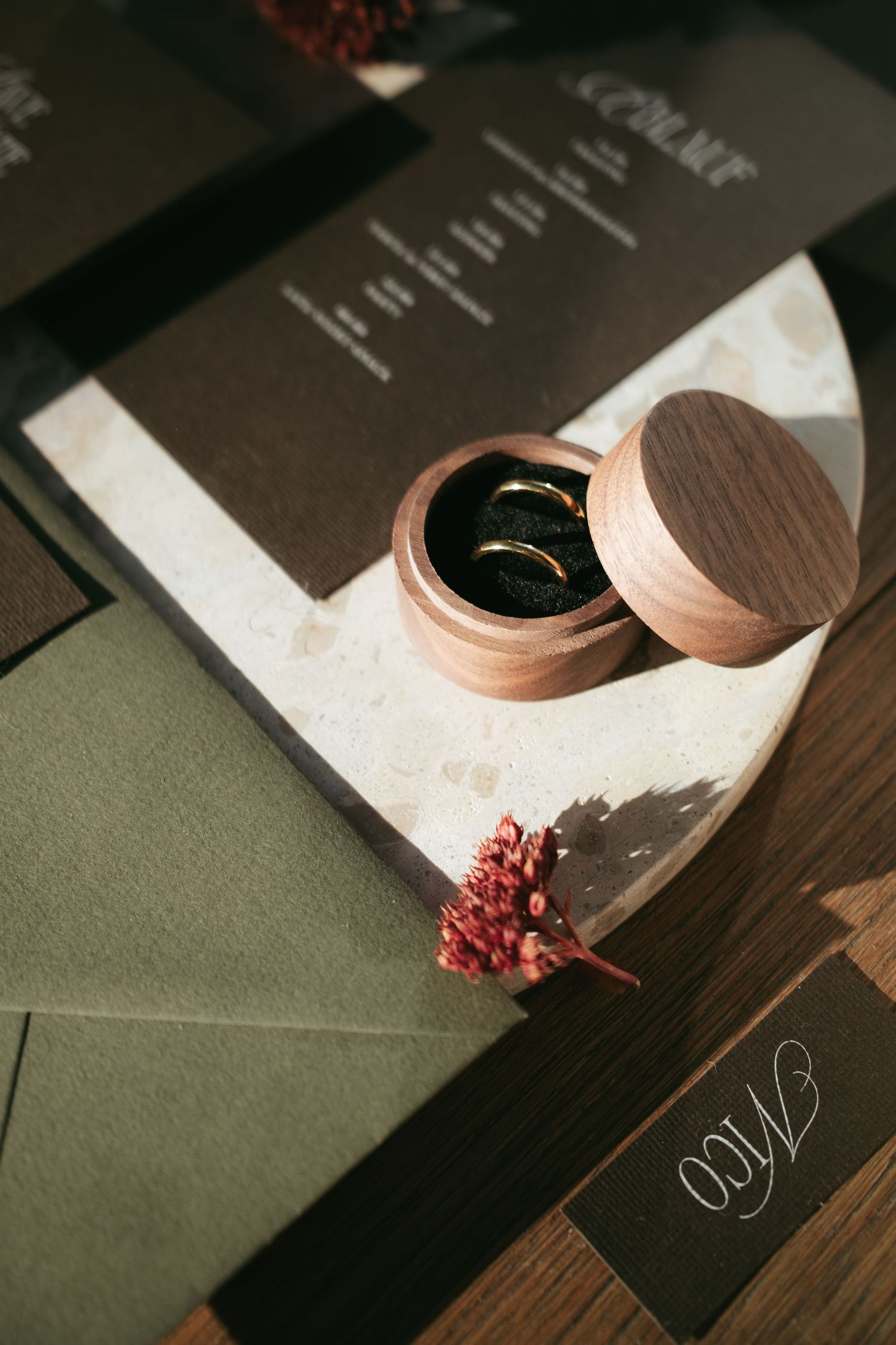 A series of elegant wedding invitations with copper foil details and floral accents arranged in a dark moody setting.