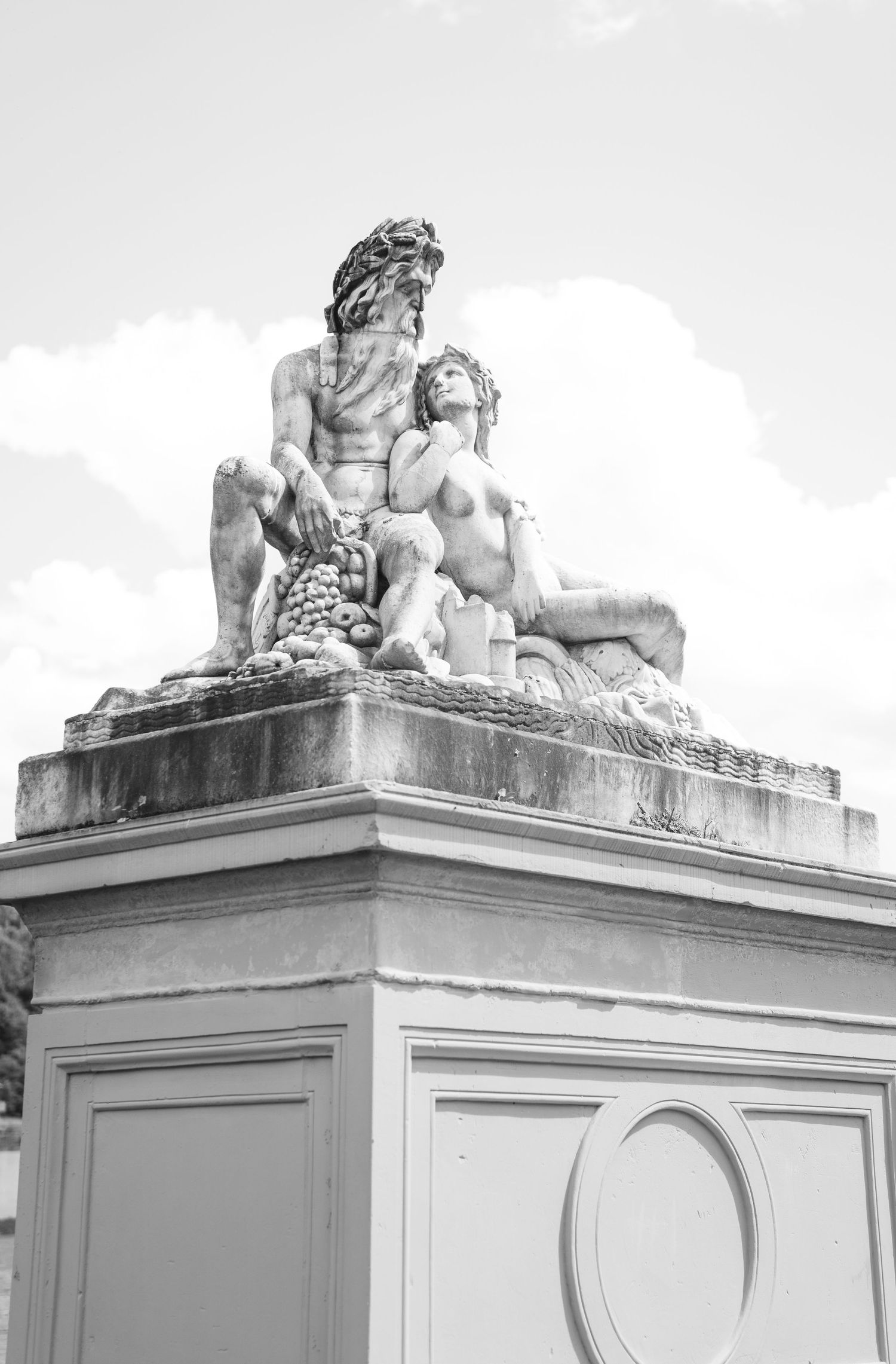 A sequence of architectural details showing classical stone sculptures of reclining figures atop identical white pedestals.