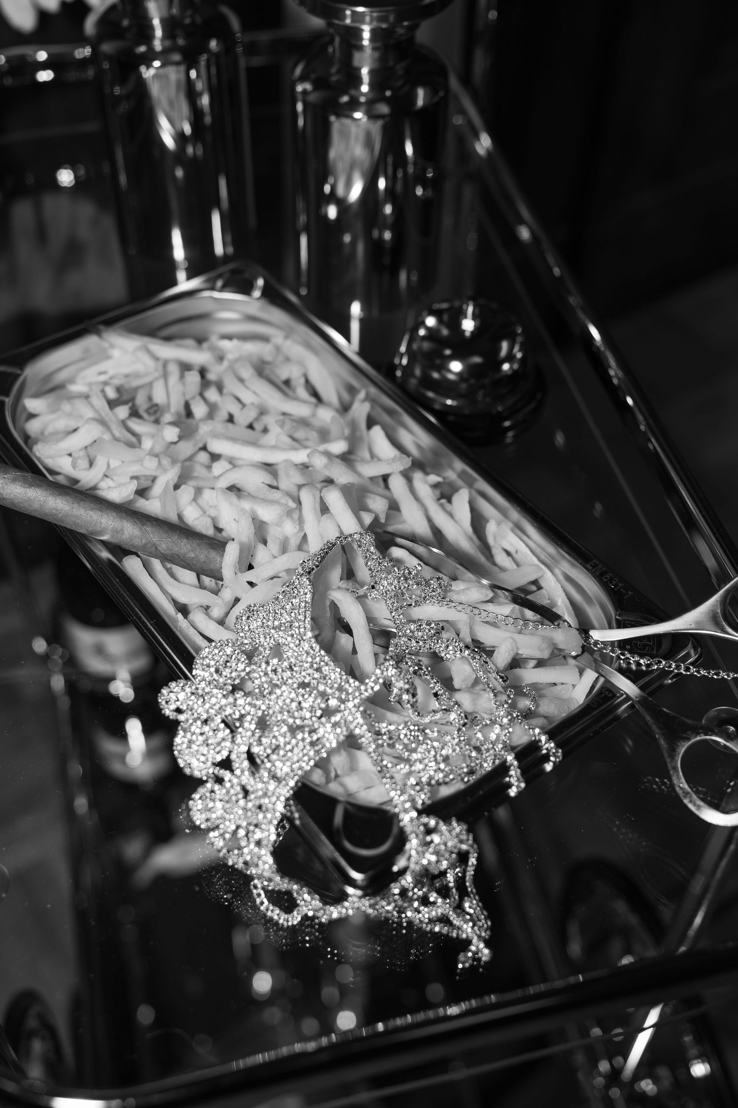 Black and white photo of sparkling diamond jewelry resting on a tray of pasta chains at a catering event.
