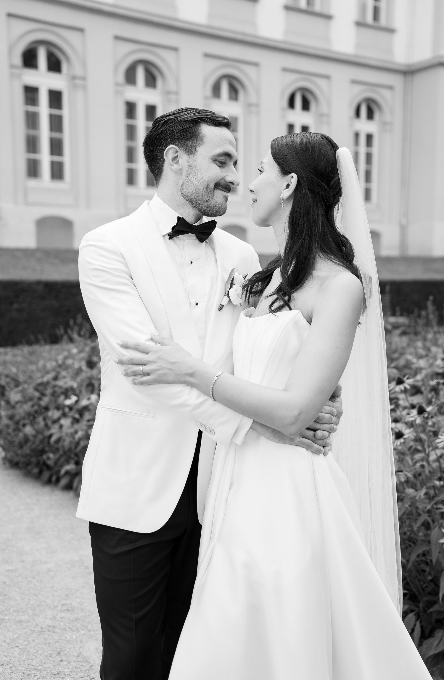 A romantic black and white wedding photo series showing a couple dancing and embracing in front of a classic building.