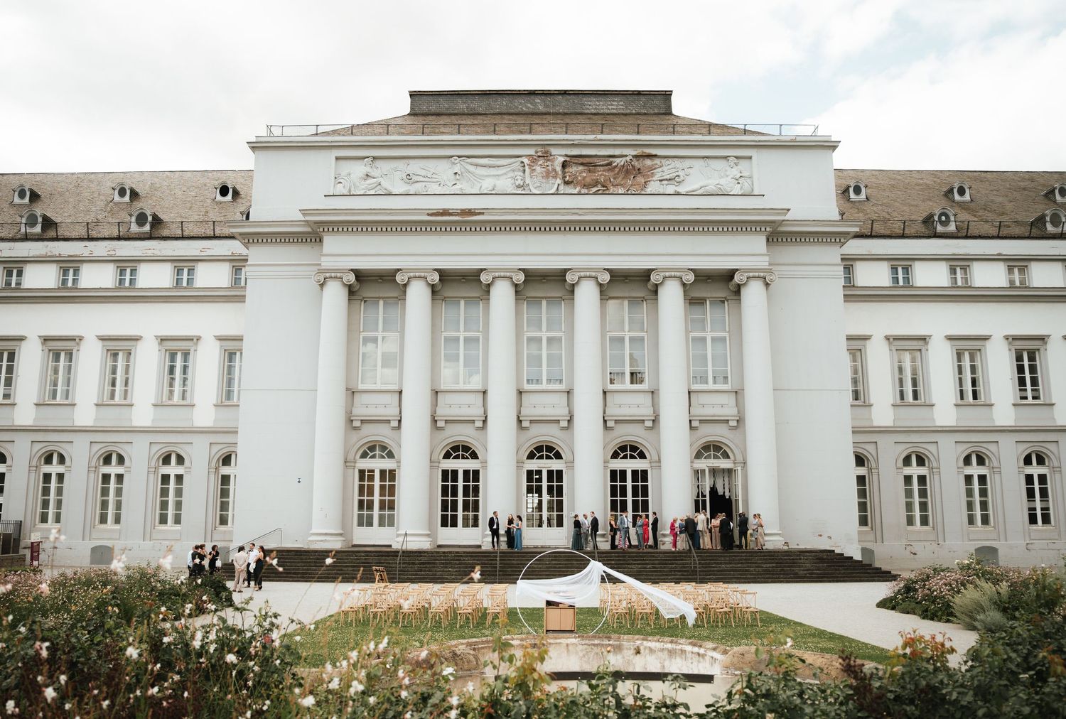 A panoramic view of a grand neoclassical government building with white columns and symmetrical architecture.