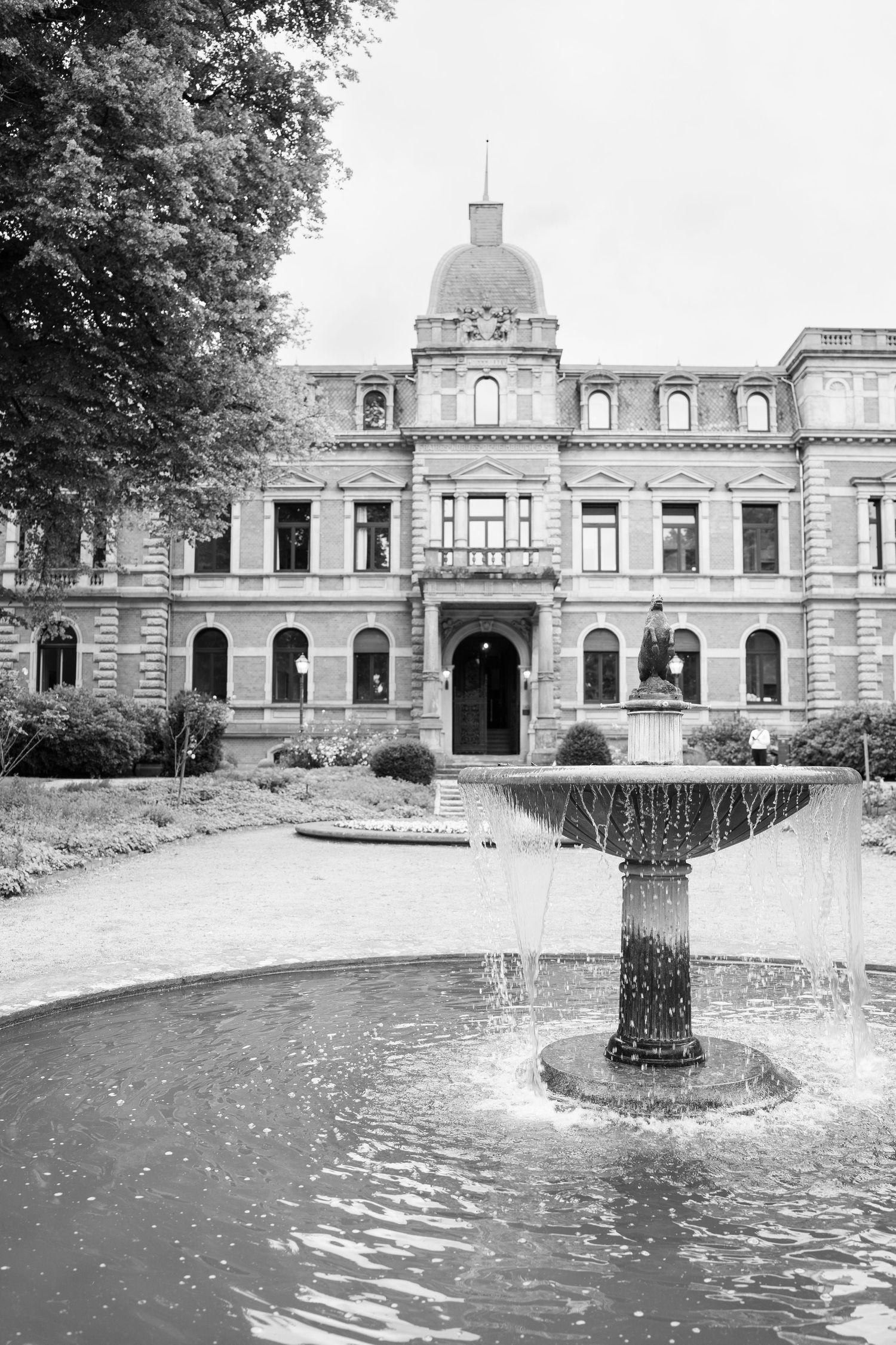 Historic stone building with domed architecture and fountain features in black and white photograph.