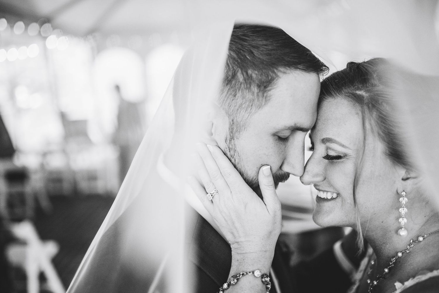Black and white wedding photo of bride and groom sharing an intimate moment under a veil.